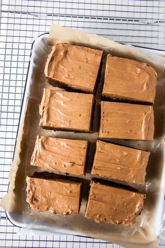 Overhead view of frosted Nutella brownies with Nutella frosting cut into squares on a tray lined with parchment paper. 