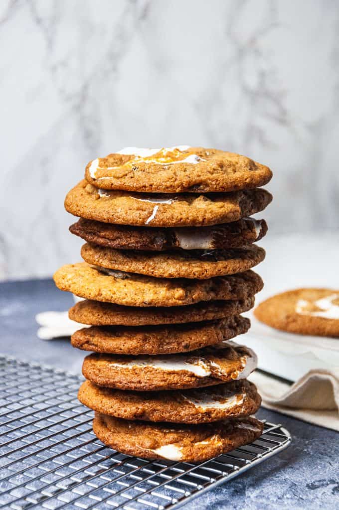 A tall stack of 10 s'mores chocolate chip cookies on the corner of a cooling rack
