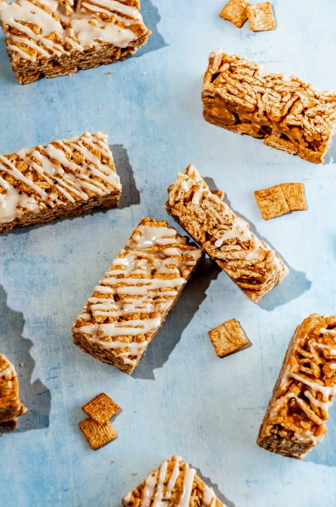 cinnamon toast crunch bars with milk icing scattered with pieces of cereal on a blue background. different angles showing all sides and textures