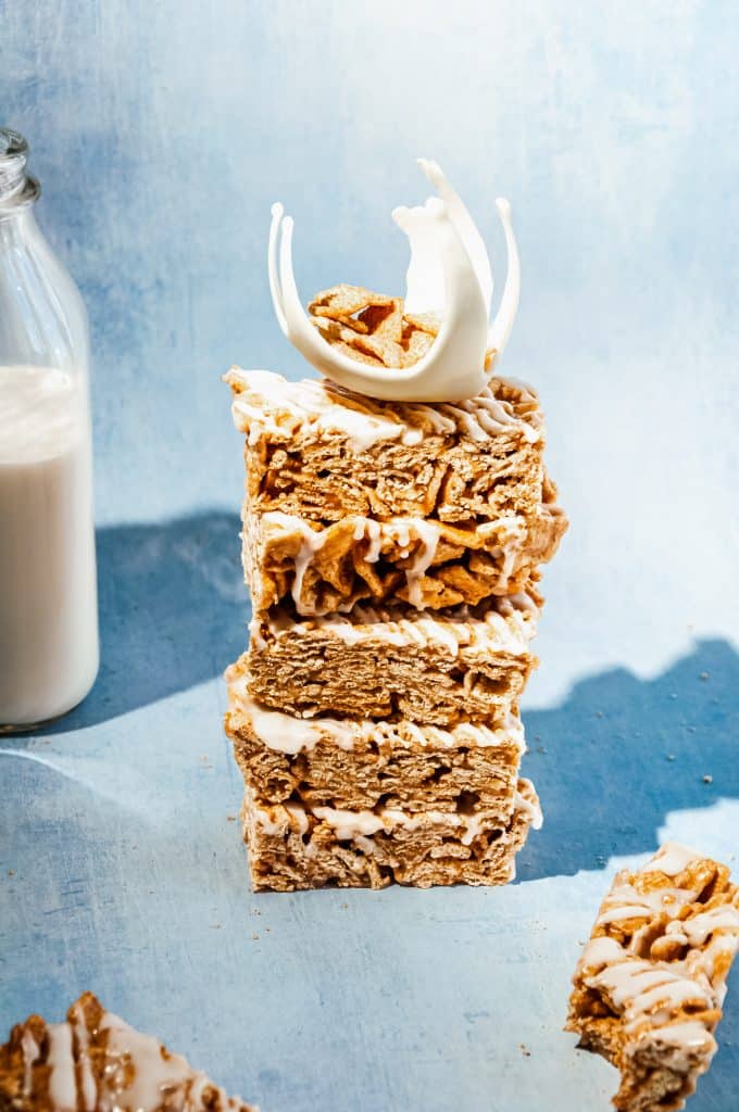 stack of 5 milk and cereal bars with cinnamon toast crunch, bottle of milk in background. Stack is topped with a white chocolate milk splash cake topper