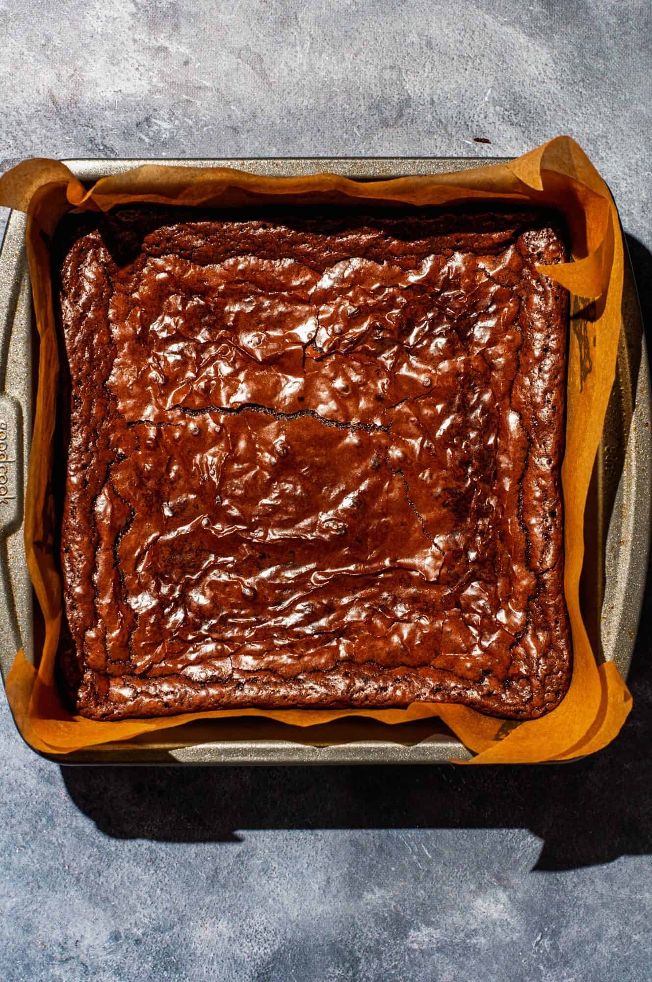 Overhead of cooked brownies in pan, showing crackly shiny texture of the top of the brownies.