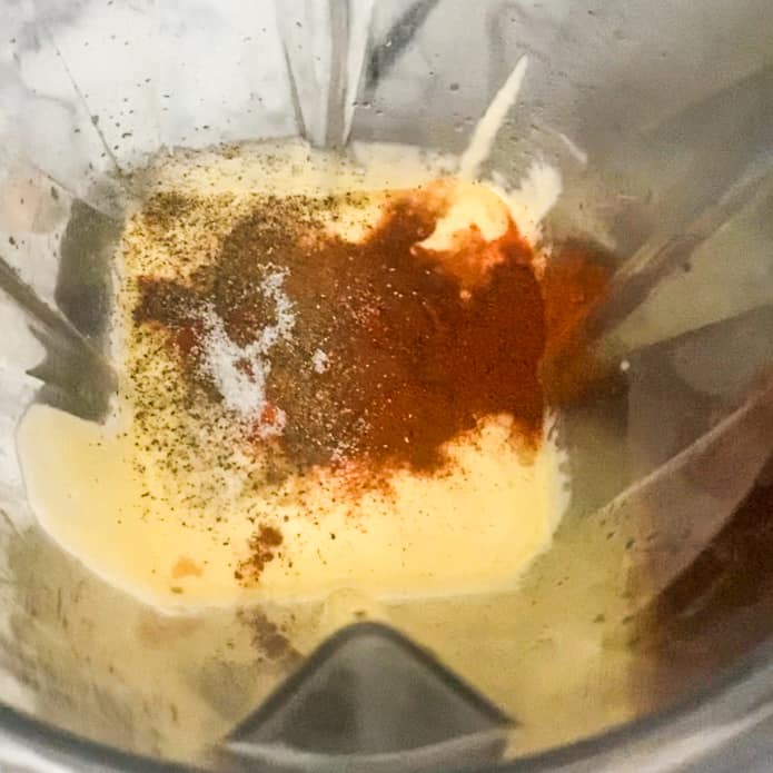 hollandaise sauce in blender with salt, pepper, chipotle chilies, and paprika on top