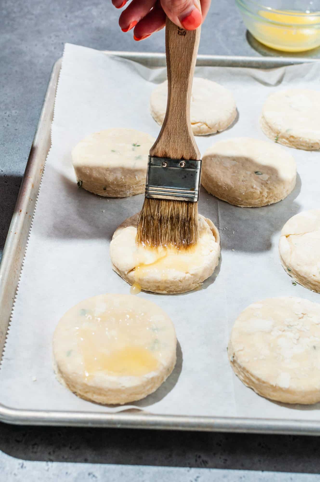 pastry brush coating raw biscuits with melted honey butter