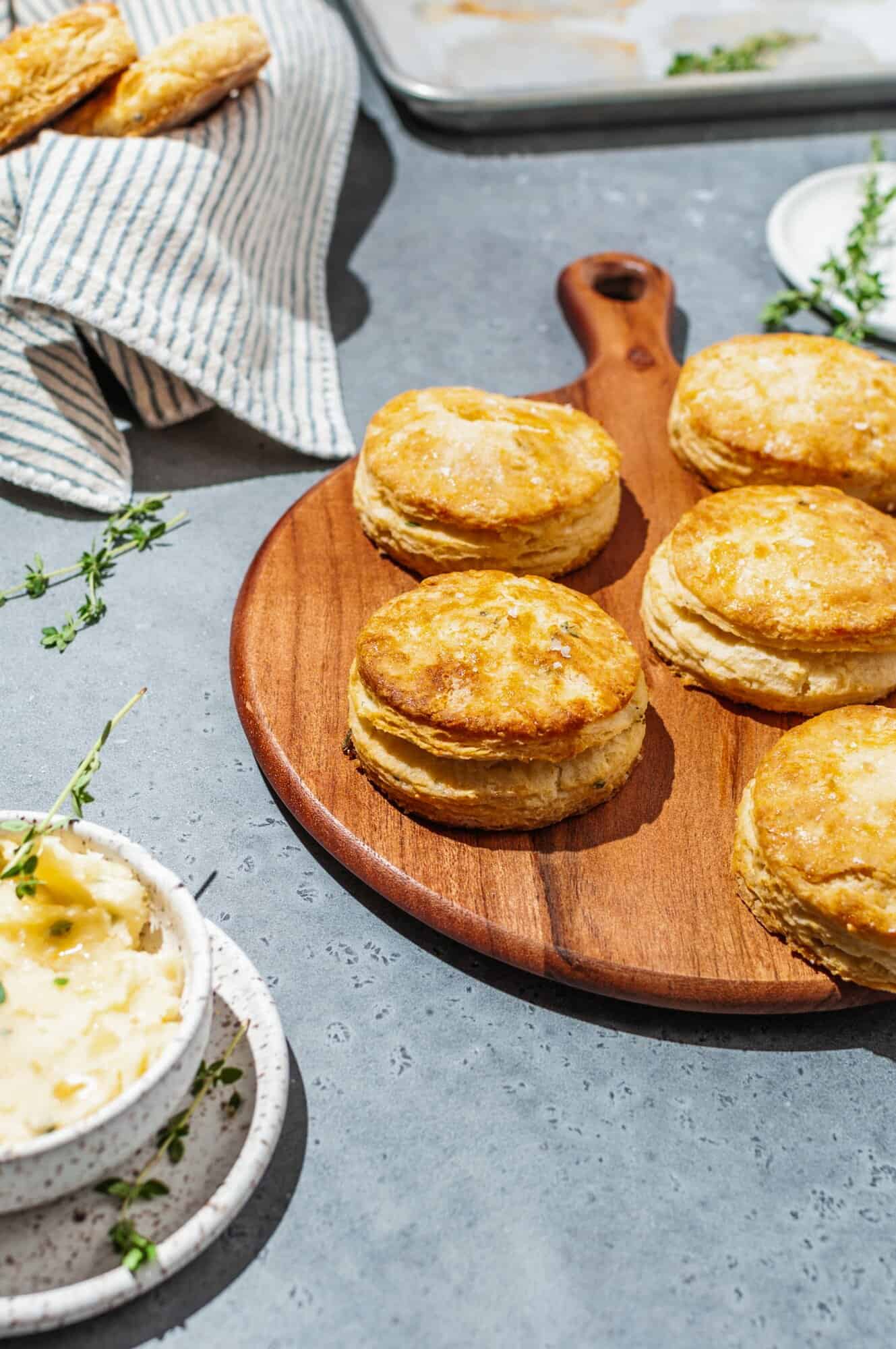 wooden serving tray with 5 flaky honey butter biscuits with thyme