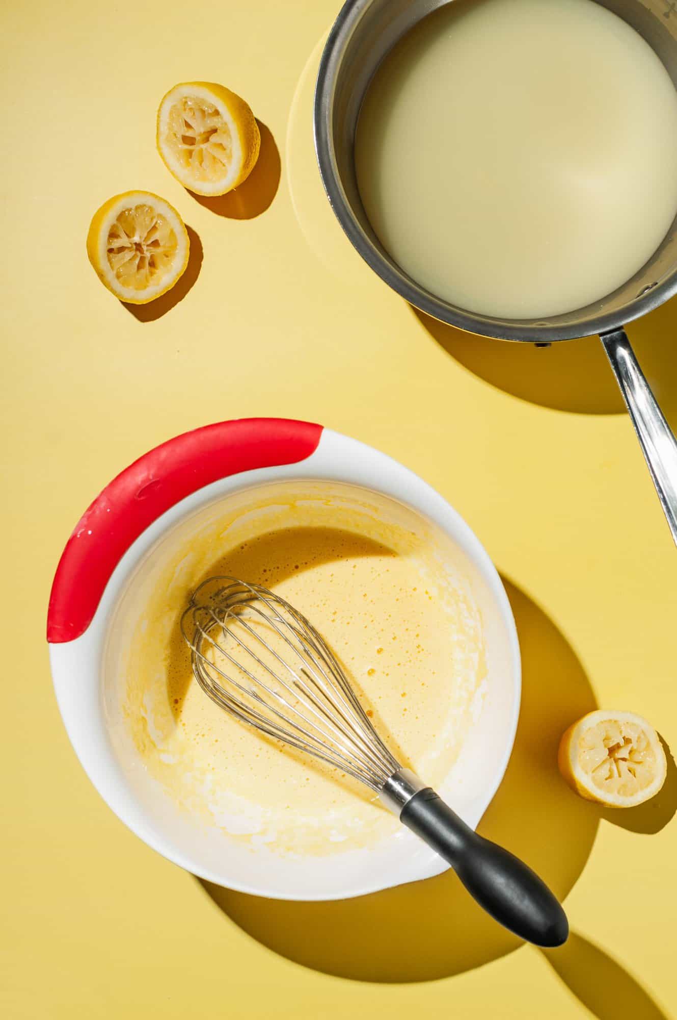 bowl with egg yolks and cornstarch, pot with lemon juice and sugar to the side