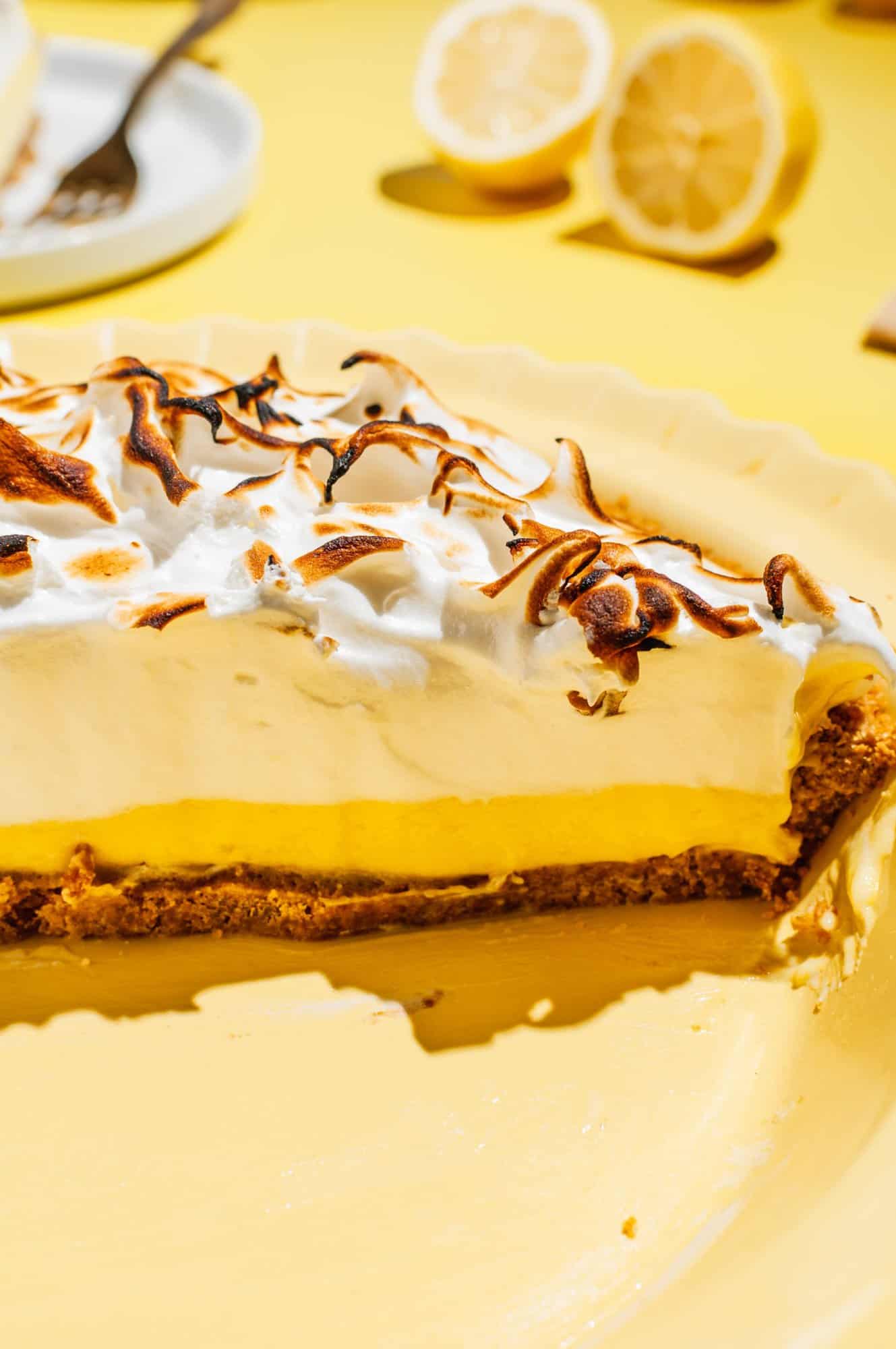 lemon meringue pie cut in half to show inside filling and graham cracker crust