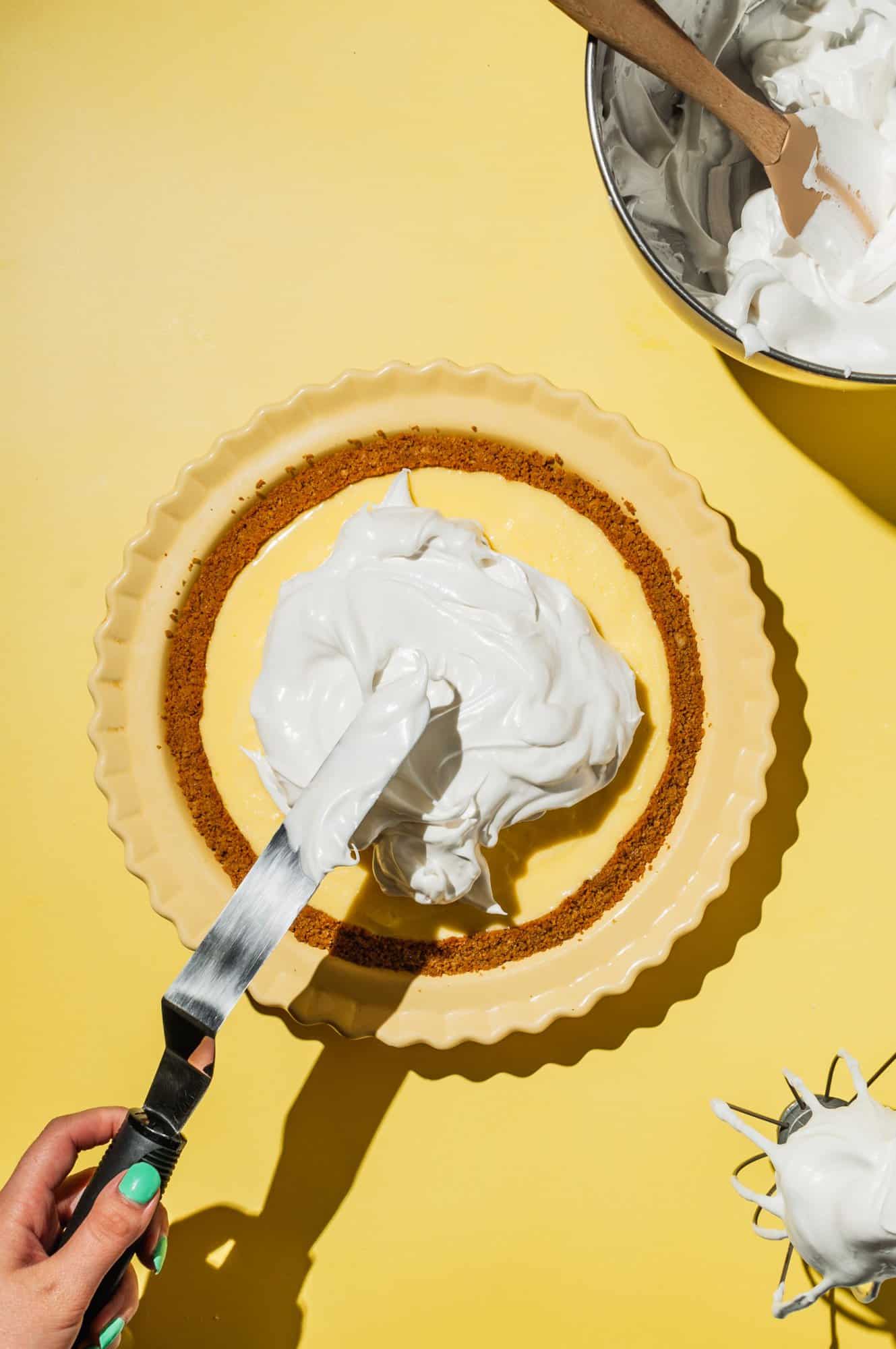 offset spatula spreading Swiss meringue onto lemon meringue pie
