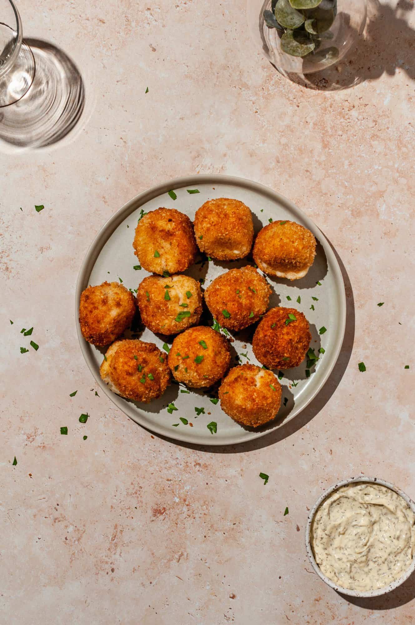 ham and cheese croquettes on a platter with aioli on the side