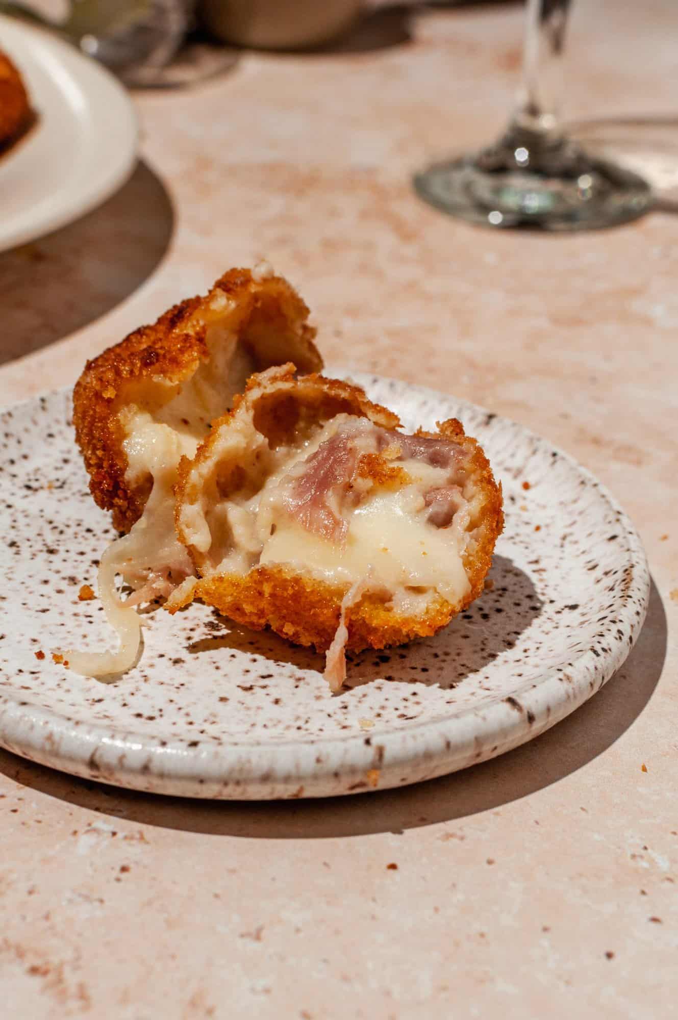 ham croquette torn open to show melty cheesy inside