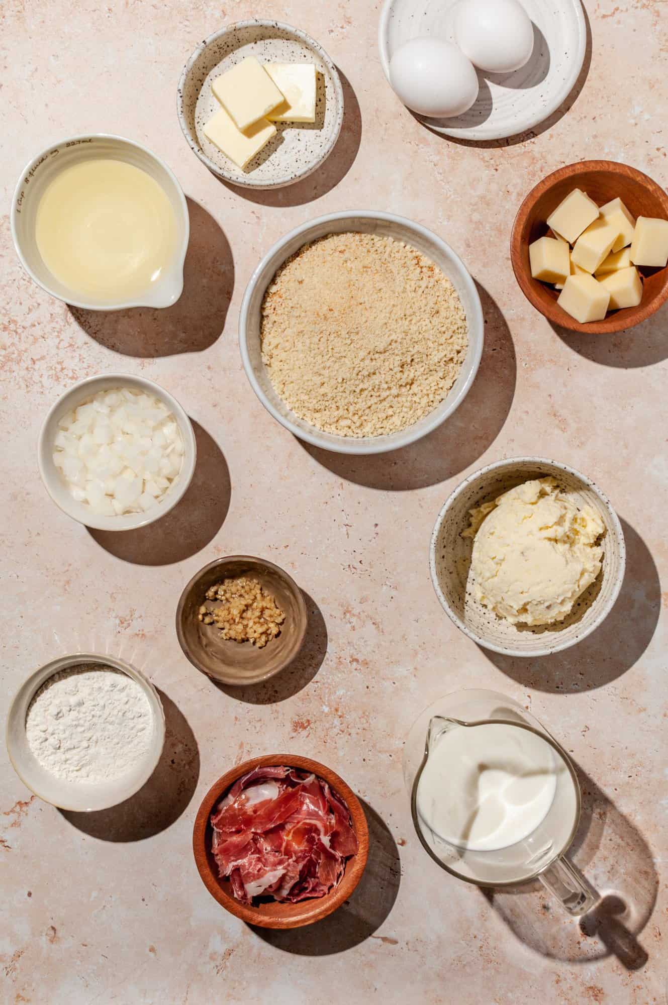 ingredients for croquettes- ham, cheese, mashed potatoes, oil, milk, garlic, onion, butter, eggs, flour, breadcrumbs