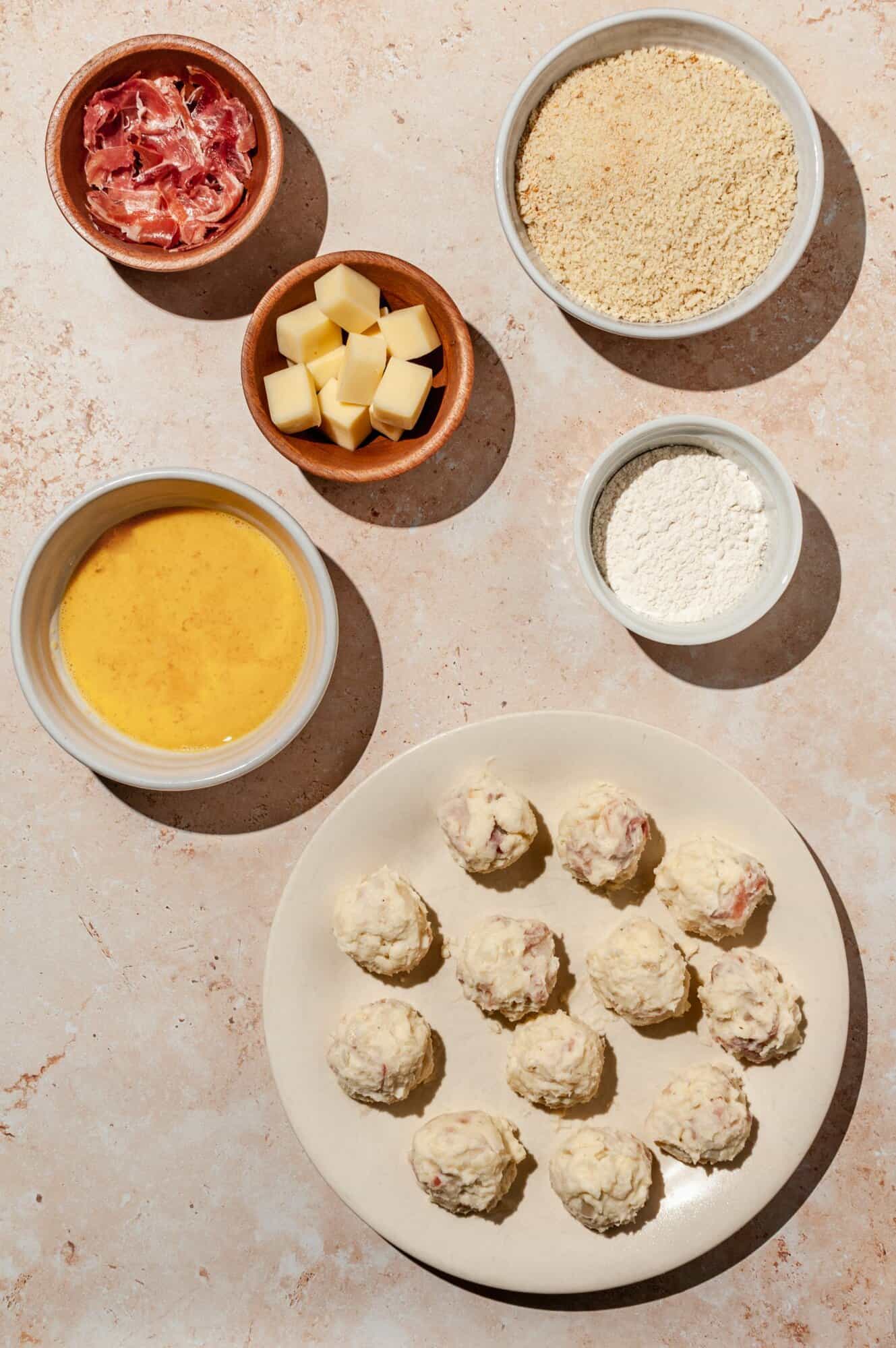 set up for making croquettes- bowls of flour, egg, breadcrumbs, cheese, ham