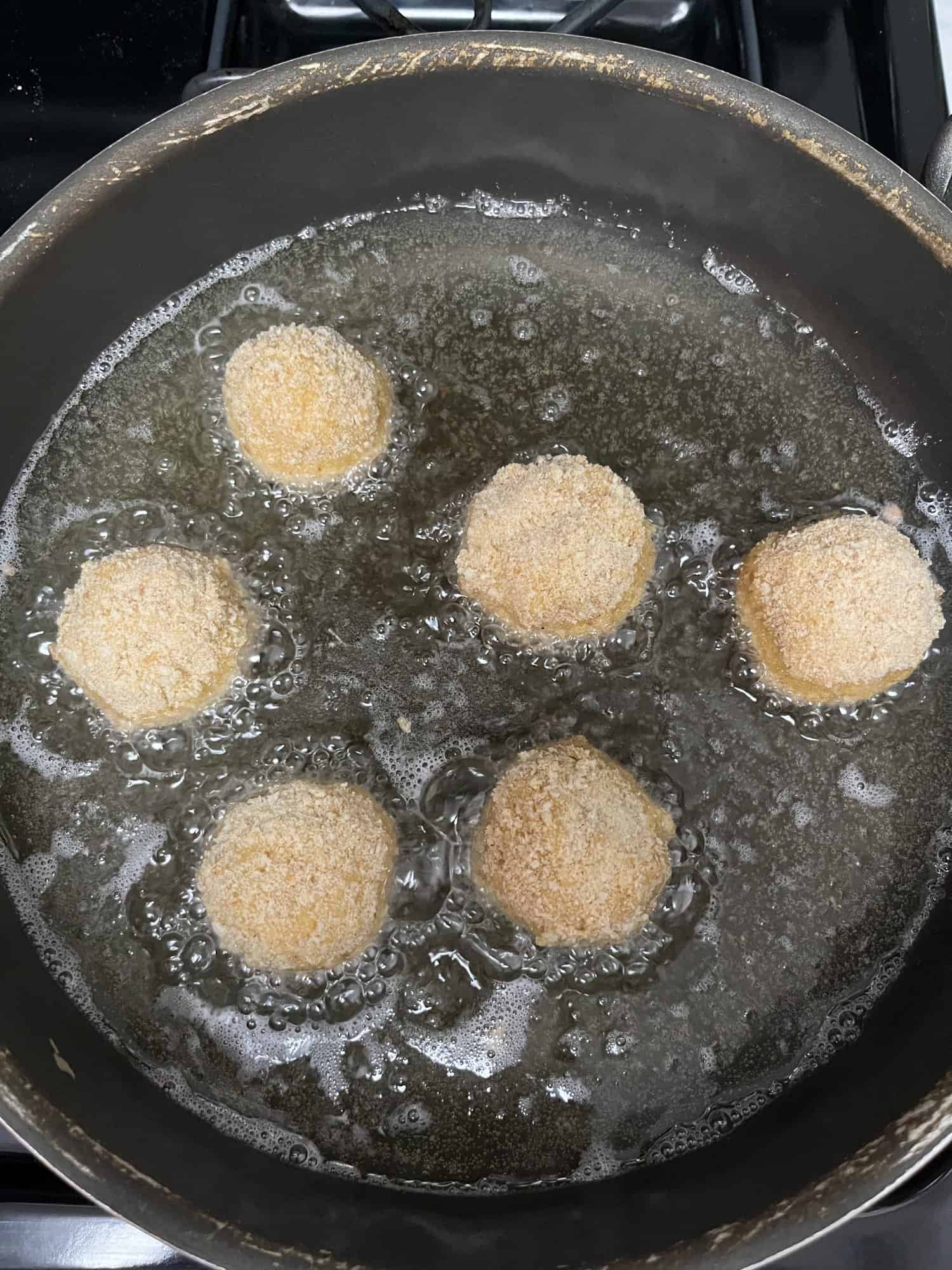 six croquettes frying in hot oil