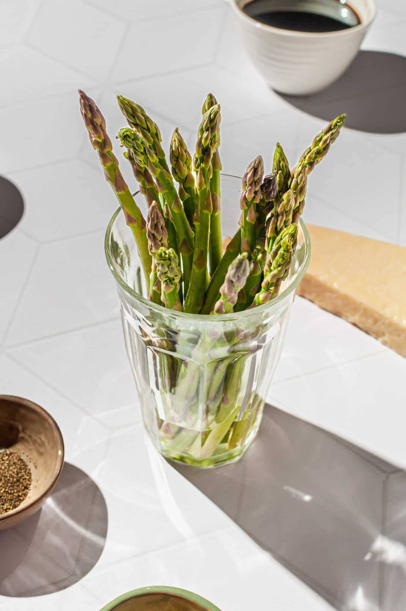 bunch of asparagus in a glass with an inch of water at the bottom