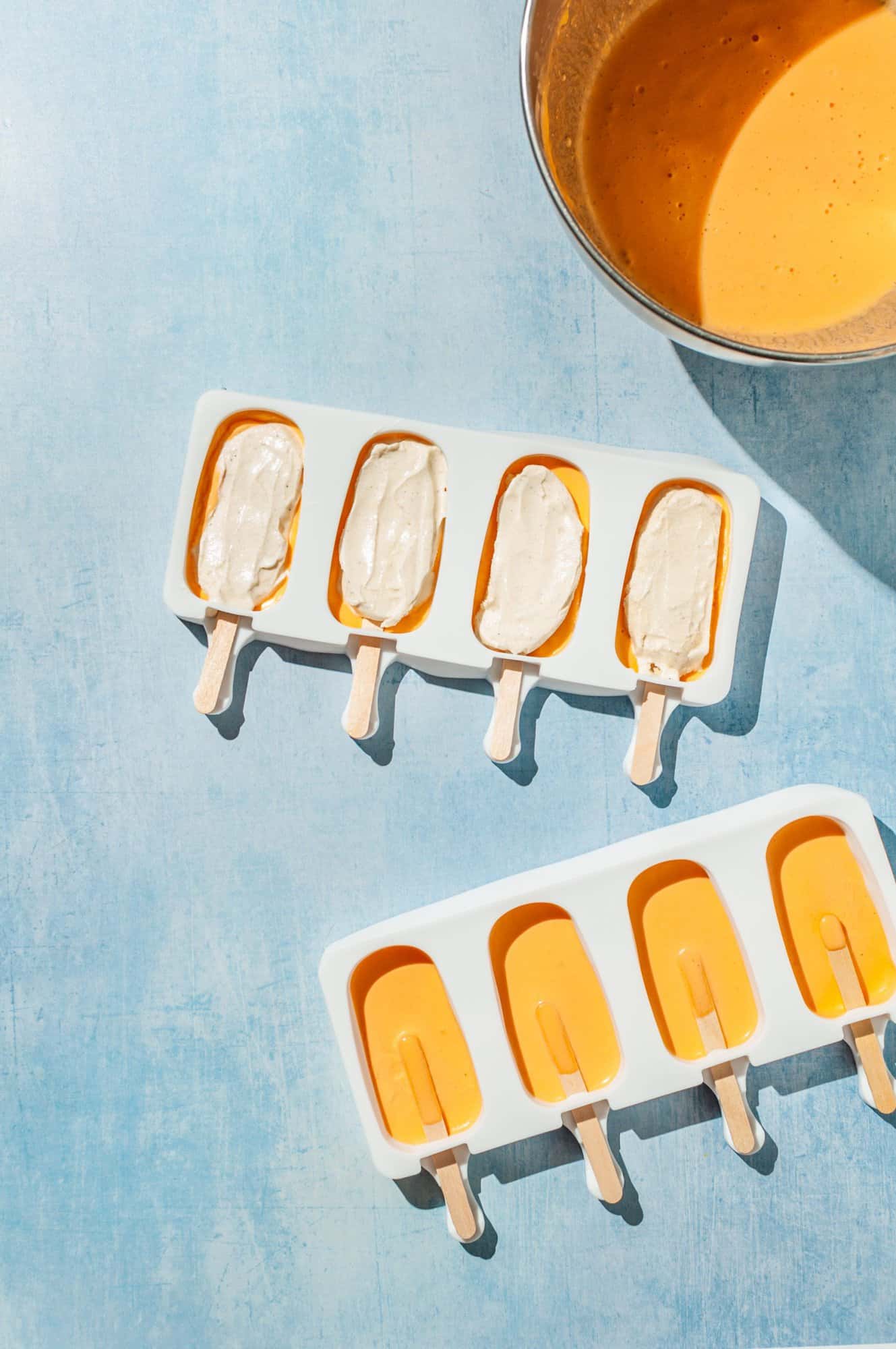 popsicle molds half-filled with orange sherbet topped with vanilla ice cream