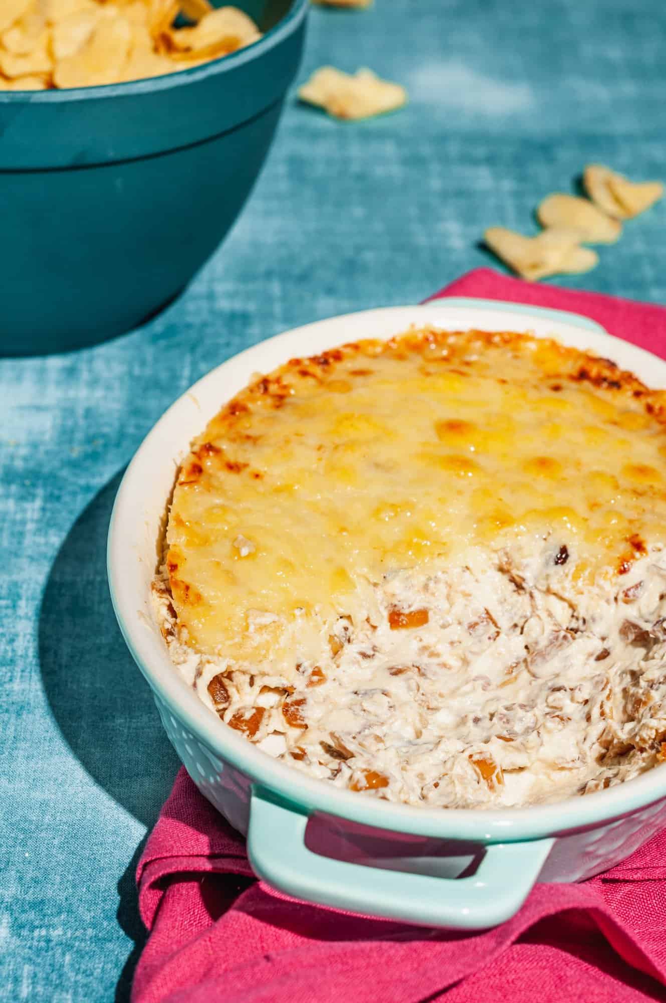 caramelized onion dip in baking dish half covered with broiled gruyere