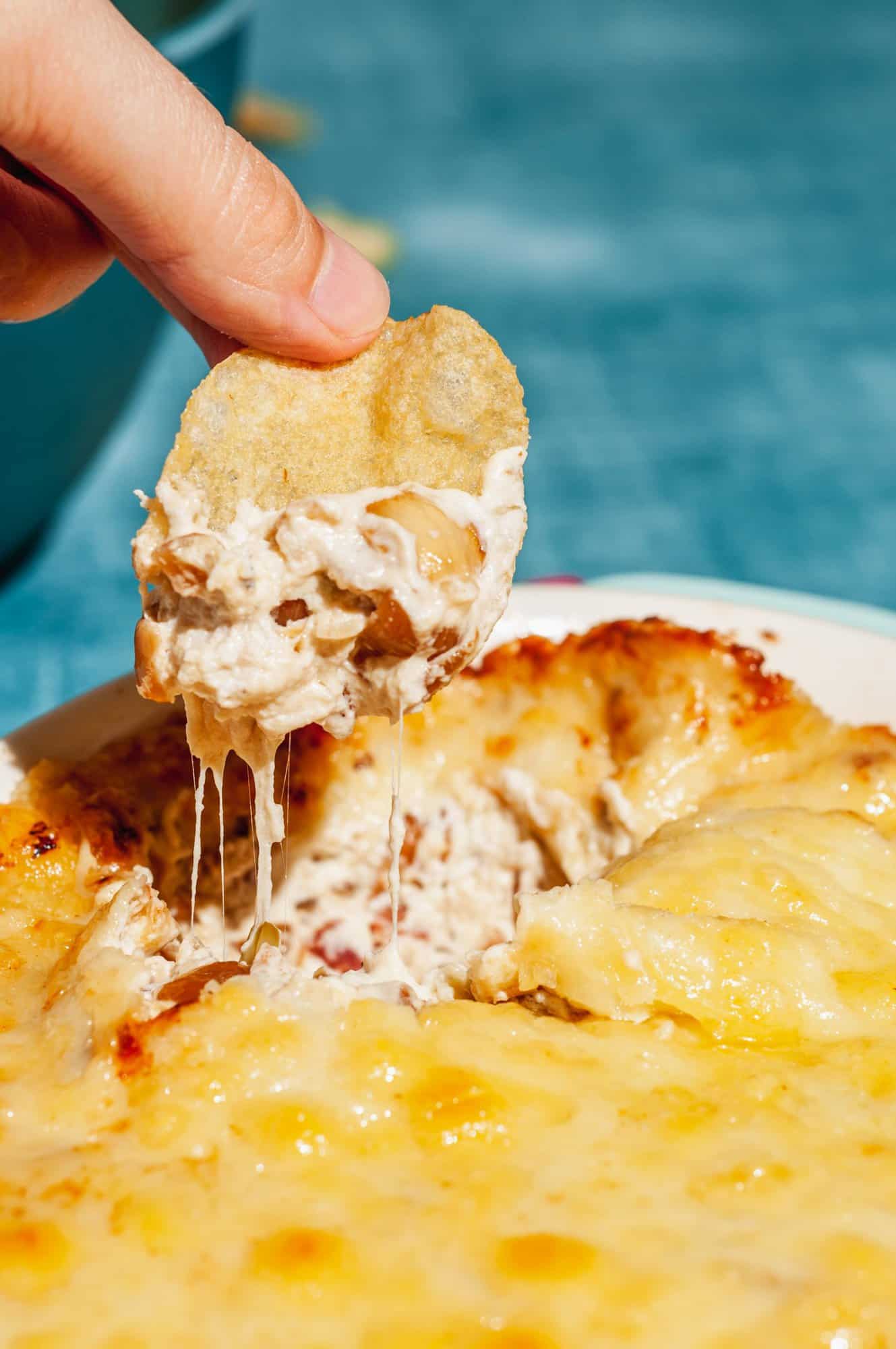 dipping chip into cheesy baked caramelized onion dip