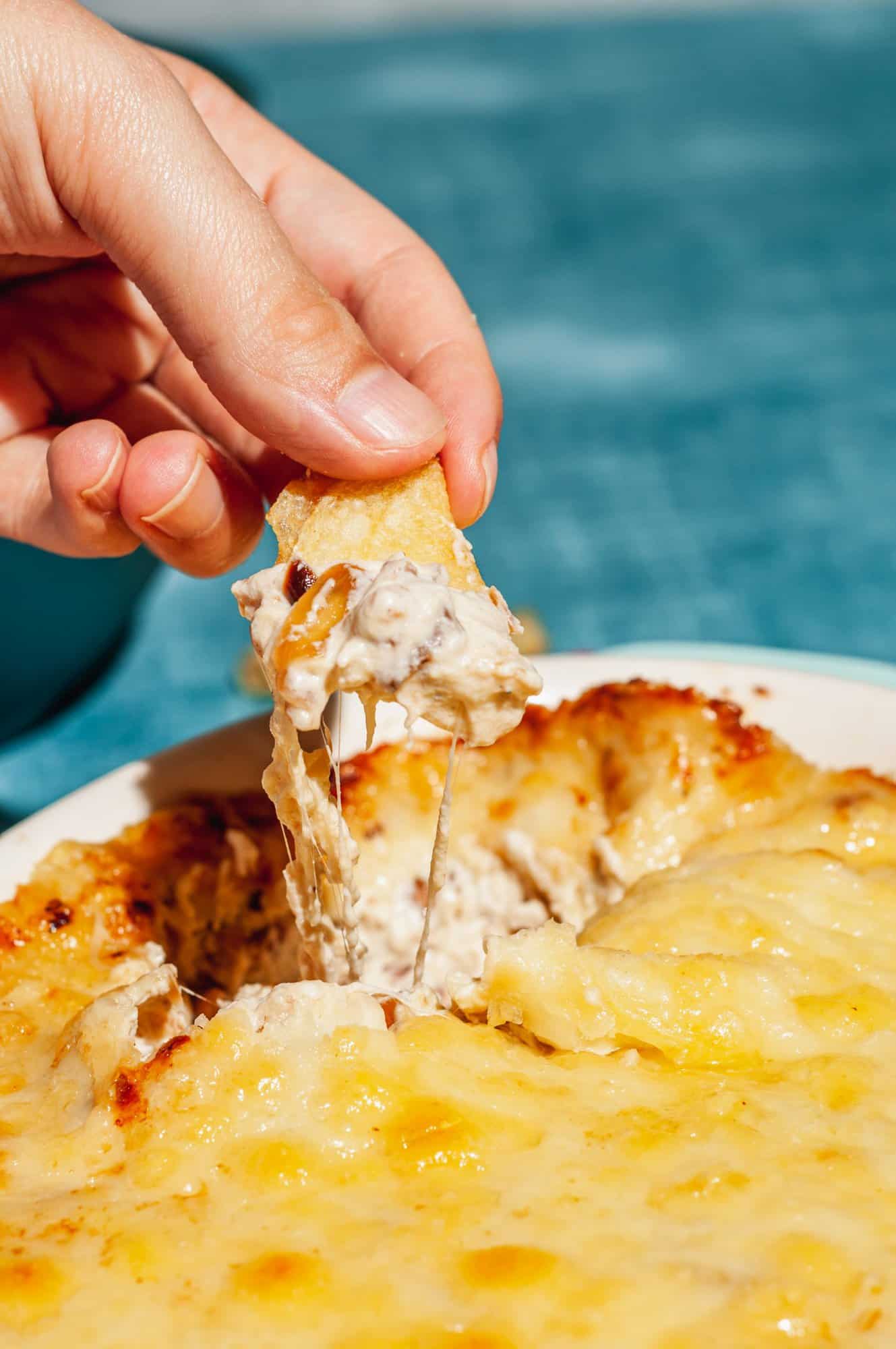 dipping chip into cheesy baked caramelized onion dip