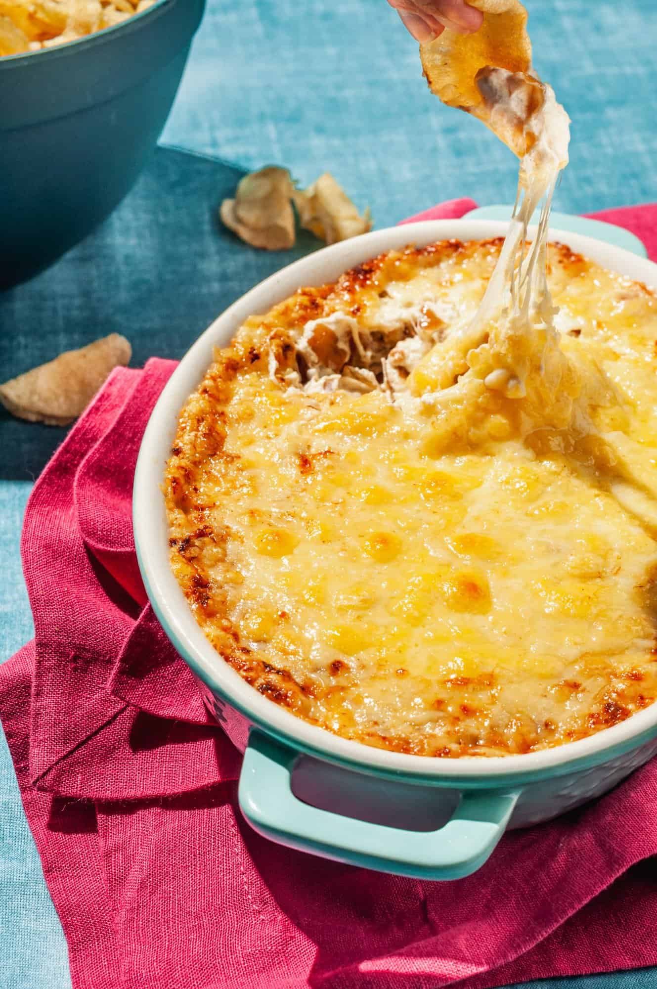 dipping chip into cheesy baked caramelized onion dip