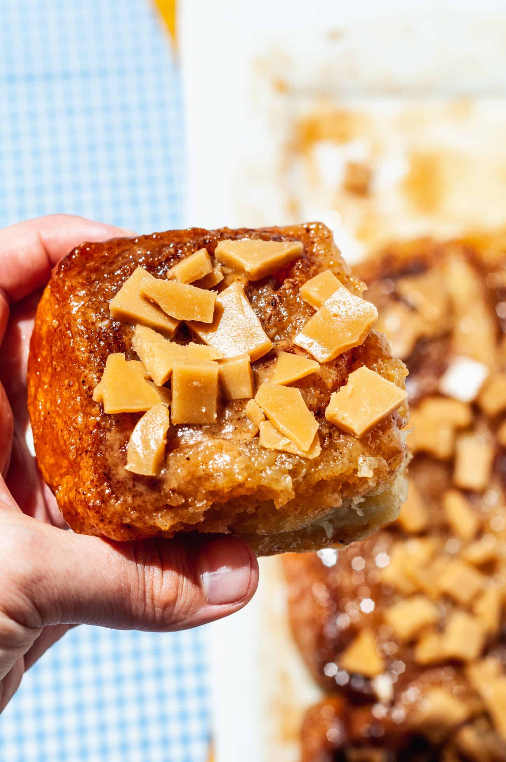 hand holding sticky toffee bun above platter