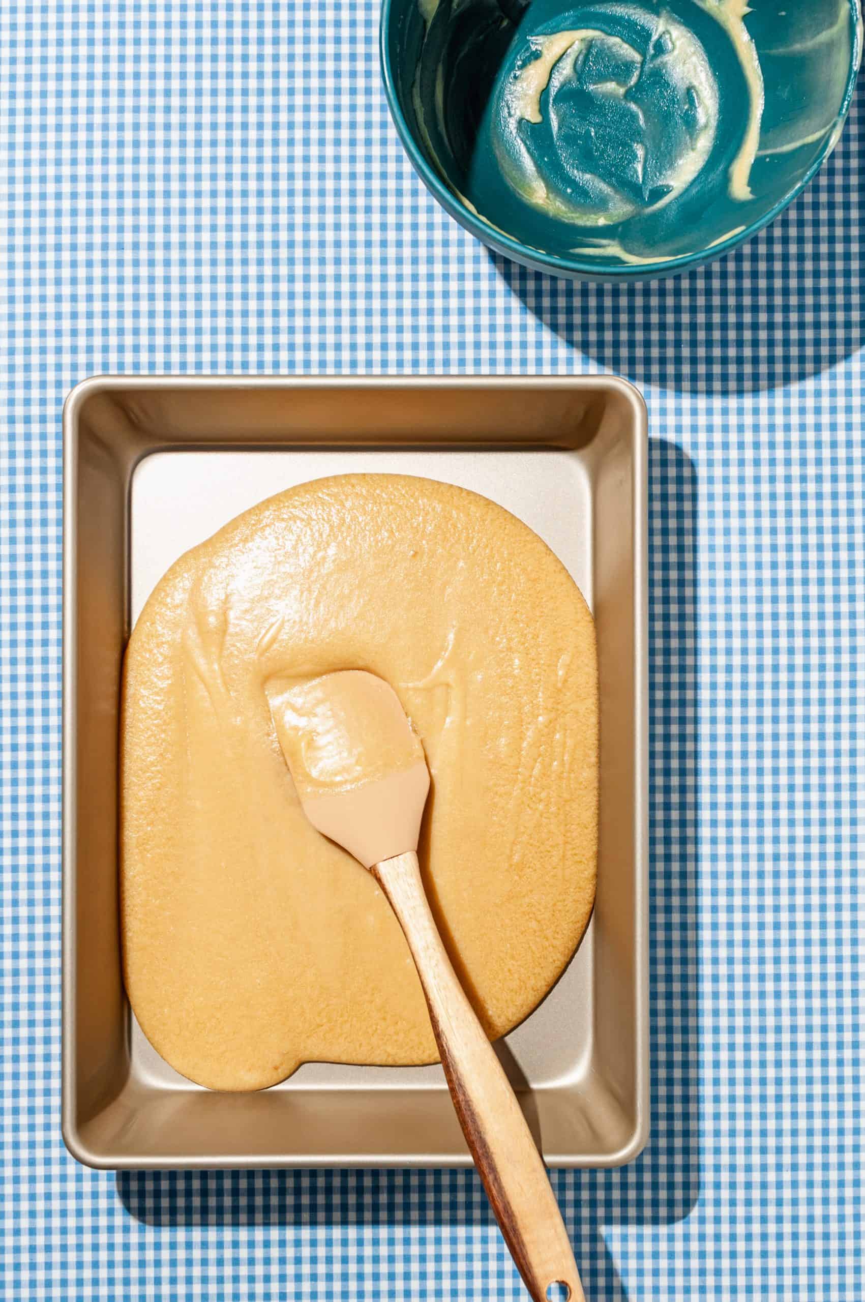 spatula spreading sticky caramel filling over bottom of pan