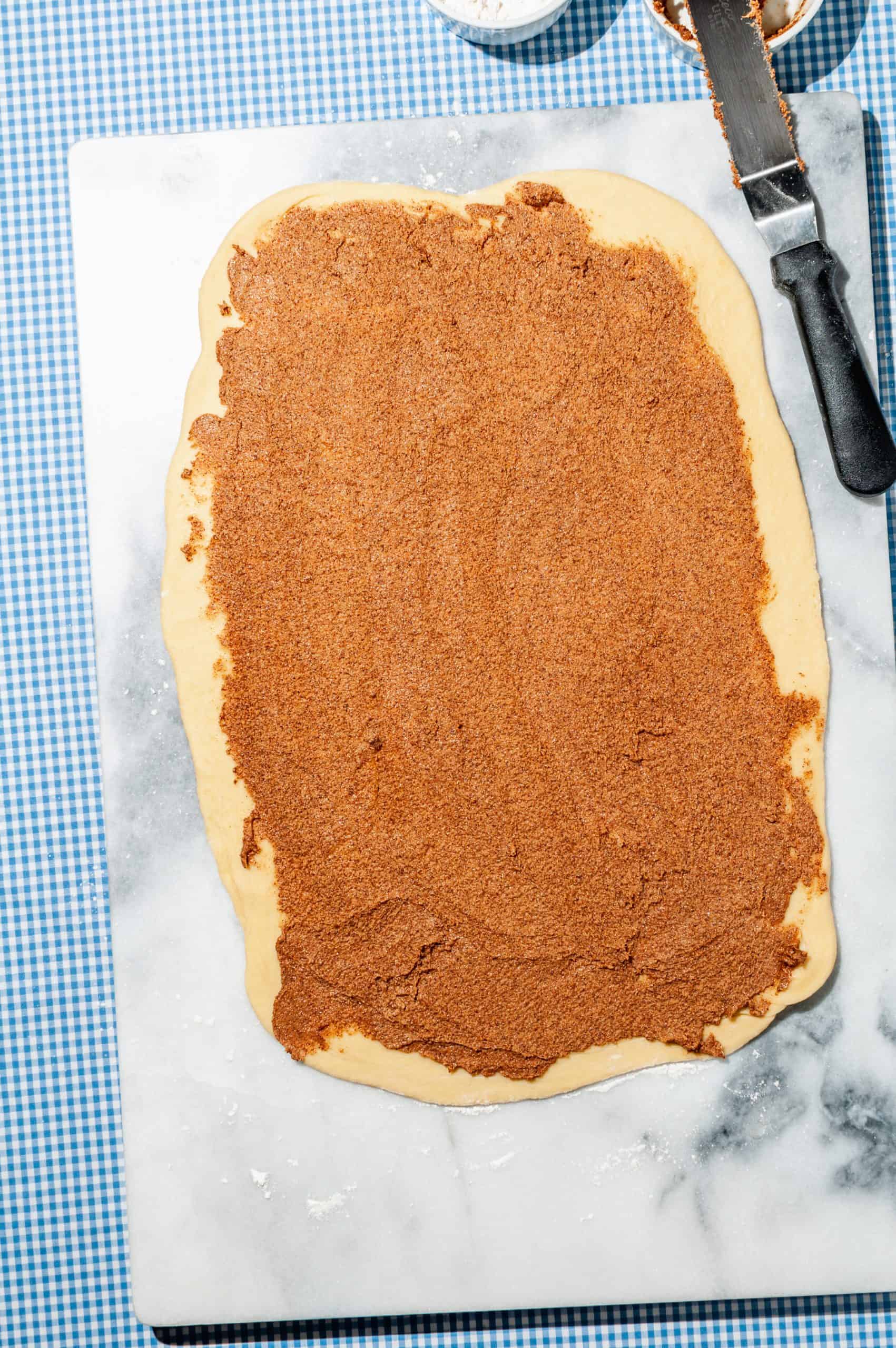 cinnamon filling spread over rolled out sticky bun dough