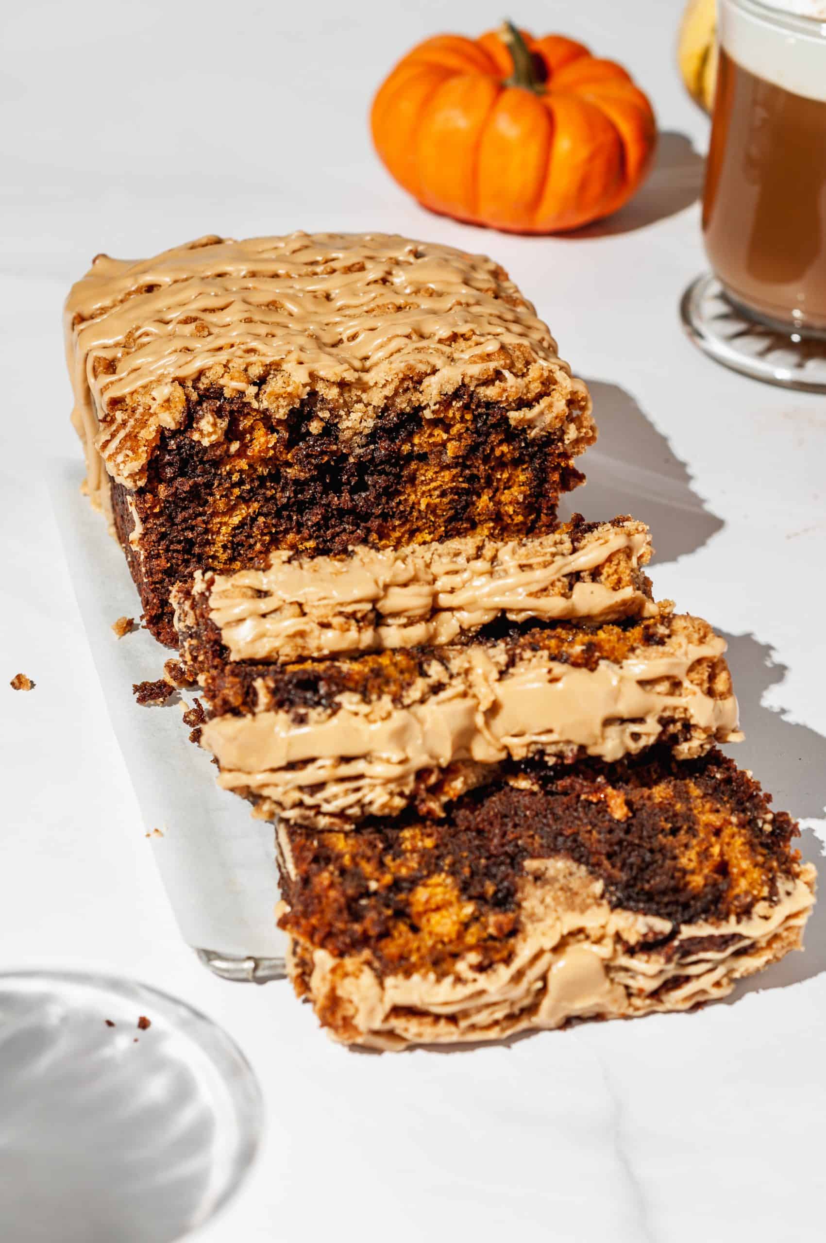 sliced streusel loaf showing marbled brown and orange inside, pumpkin spice latte in back