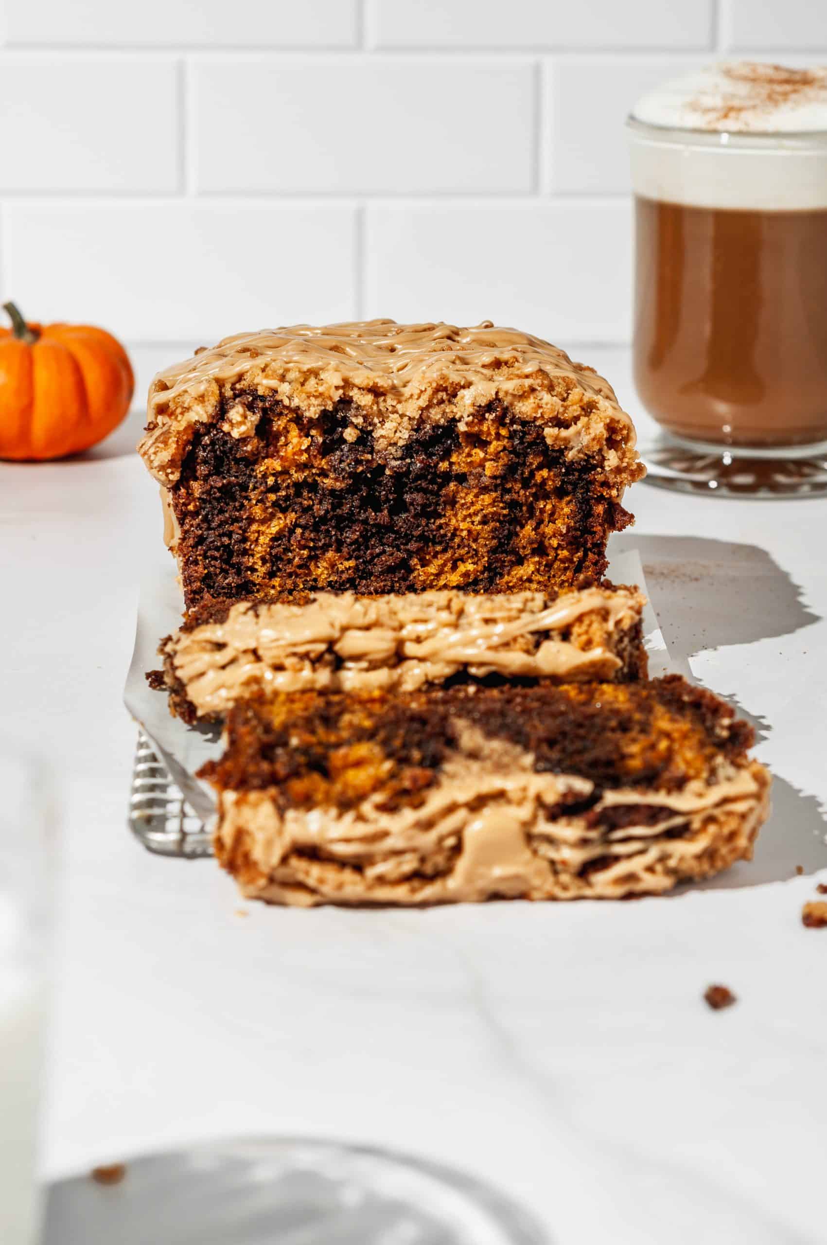 sliced streusel loaf showing marbled brown and orange inside, pumpkin spice latte in back