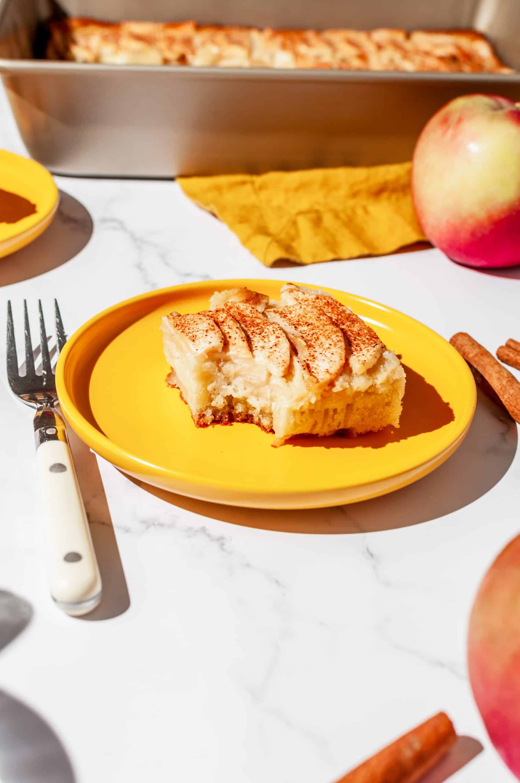 piece apple snack cake on a plate with a bite taken out, fork on the side