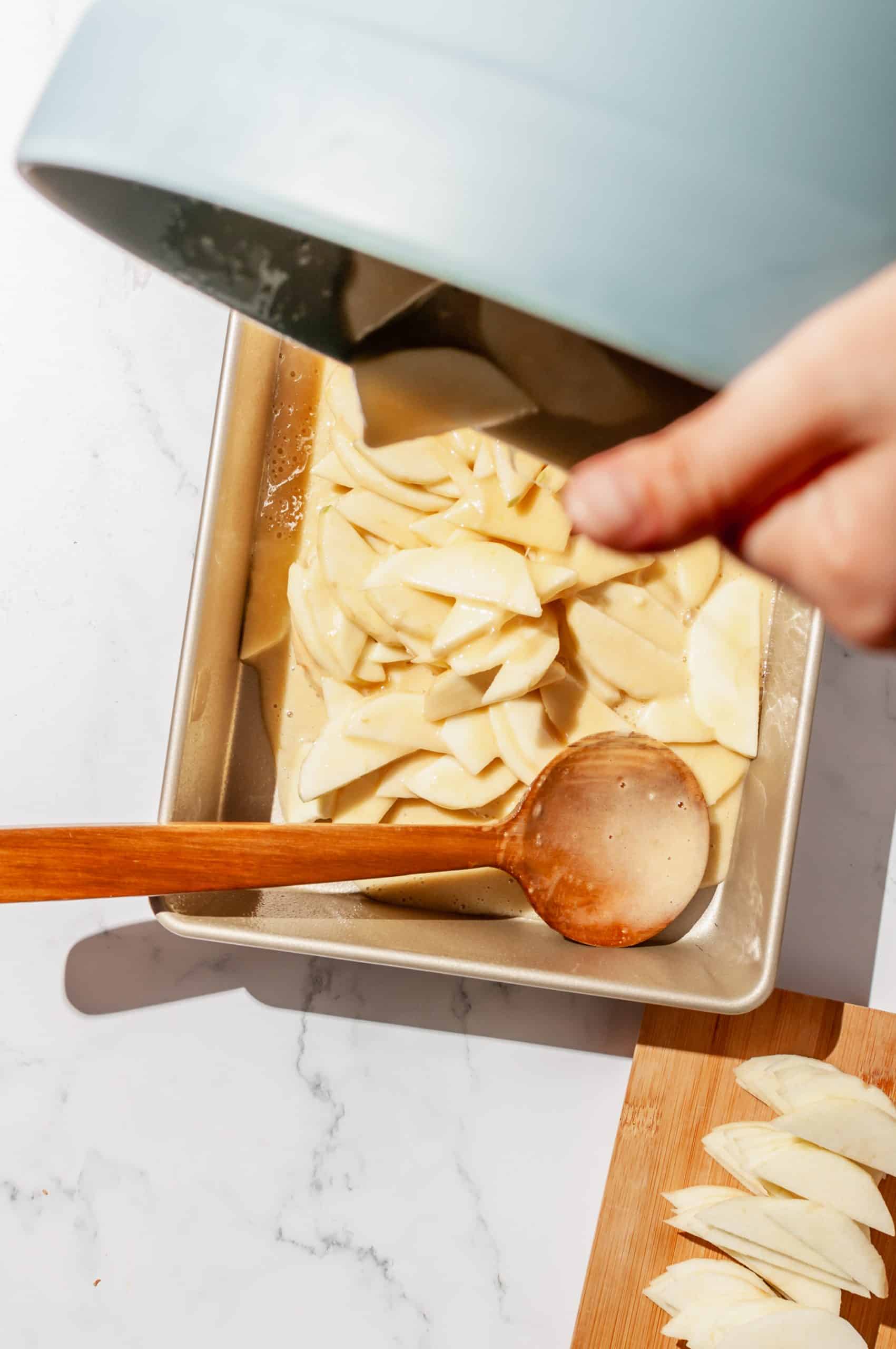 pouring apple snack cake batter from bowl into greased cake pan