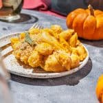 plate of pumpkin mac and cheese with sage breadcrumb topping, mini pumpkin behind plate