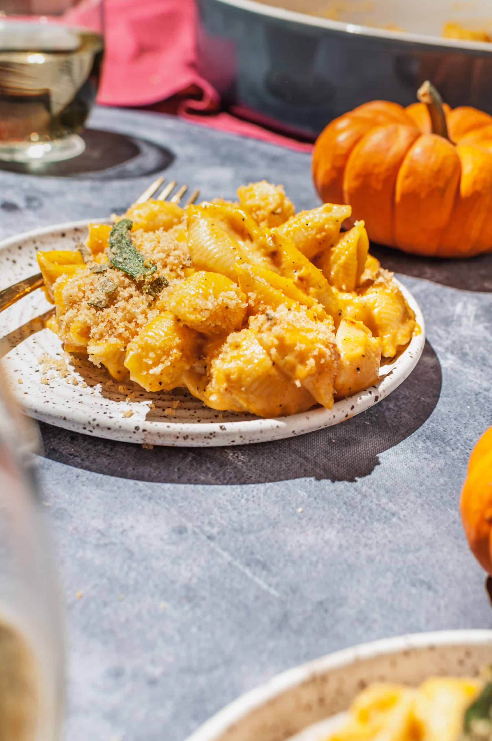 plate of pumpkin mac and cheese with toasted sage breadcrumbs on top, pumpkin in background