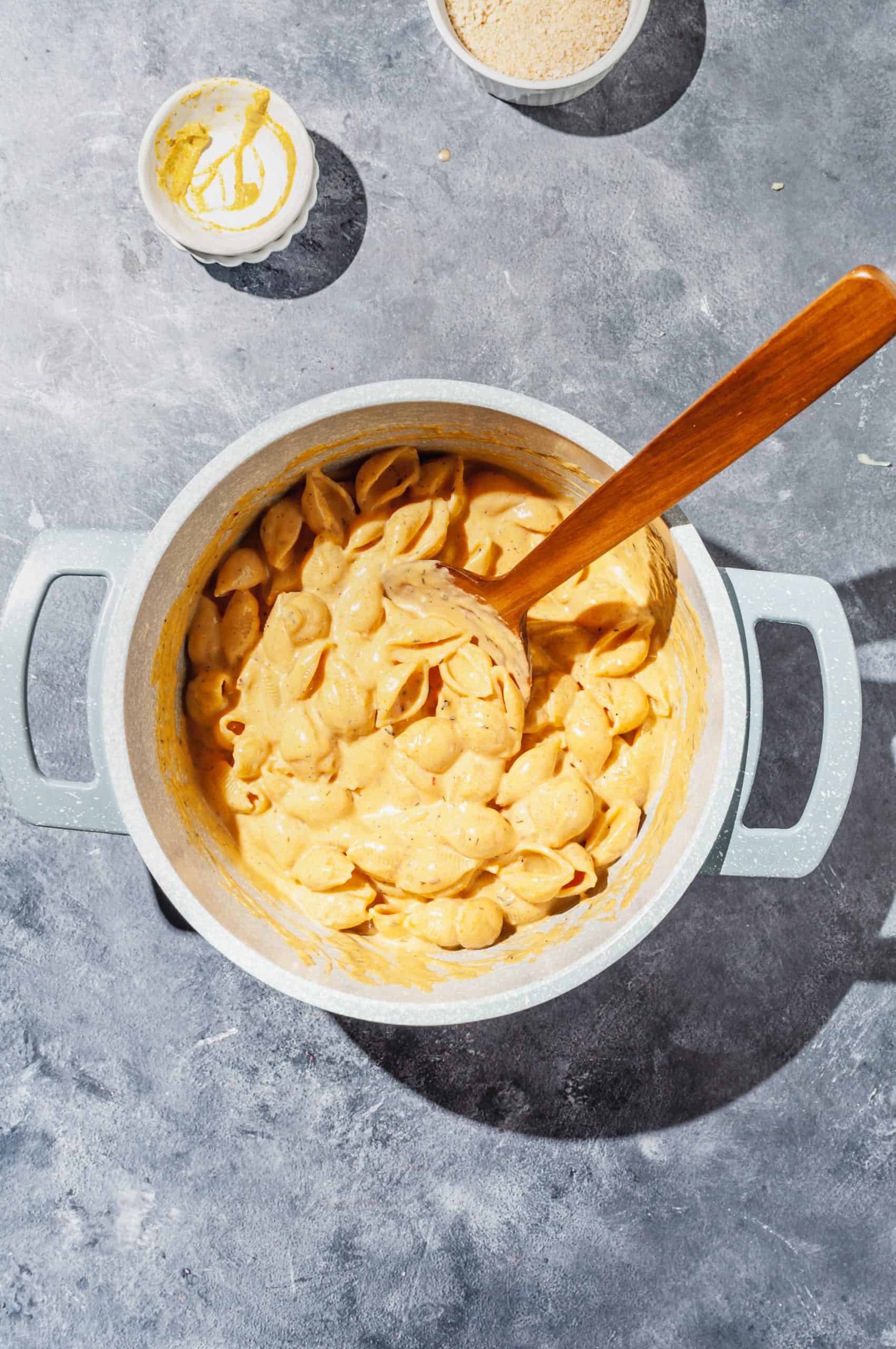 creamy pumpkin mac and cheese in pot with wooden spoon