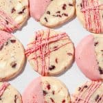 overhead close up of cranberry shortbread cookies decorated with pink white chocolate patterns and sanding sugar