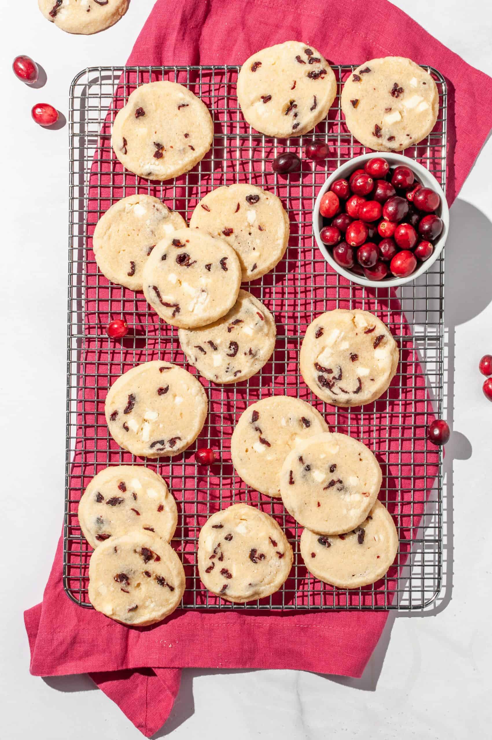 cranberry white chocolate shortbread on a cooling rack with a small bowl of fresh cranberries