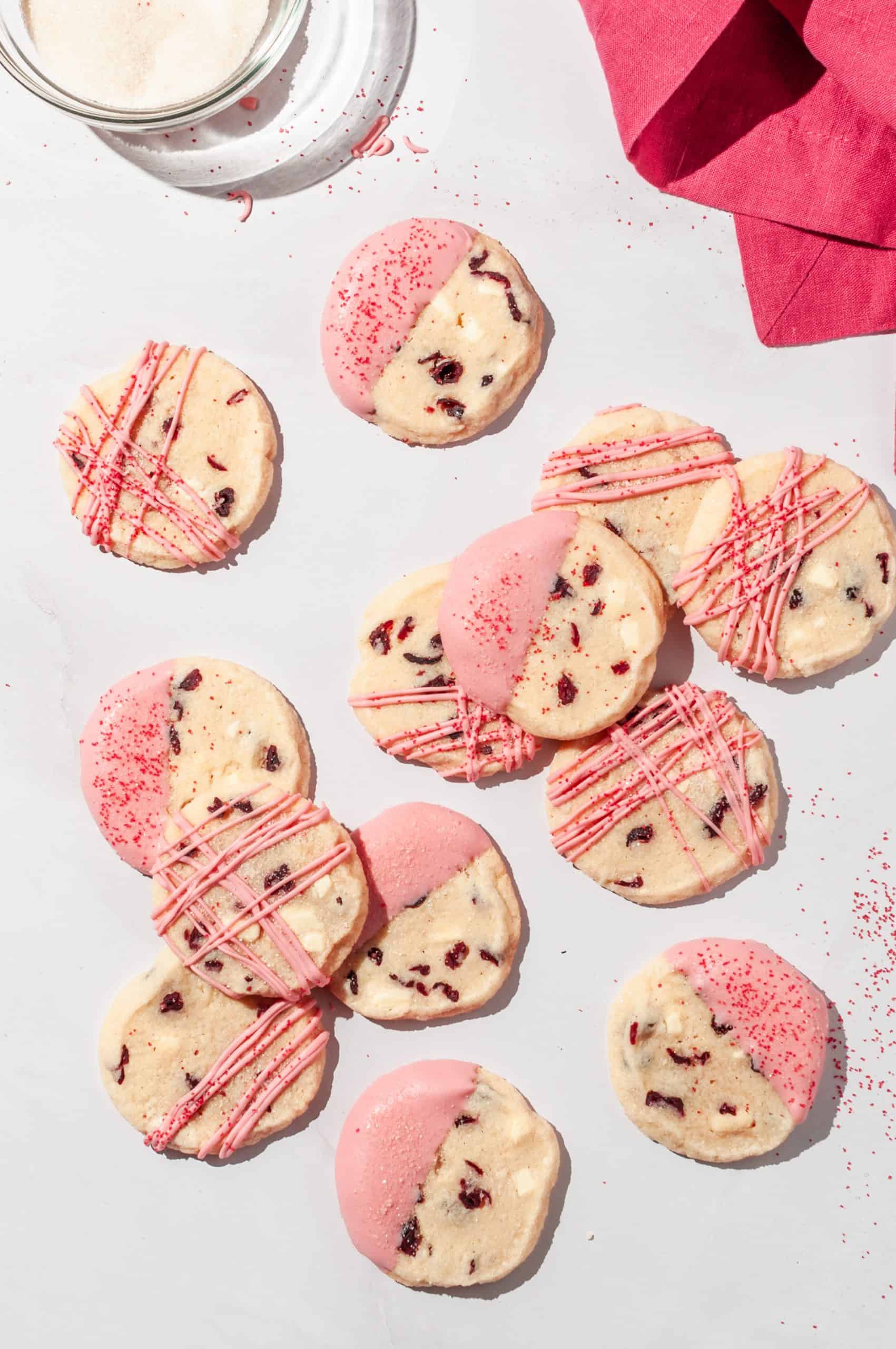 cranberry shortbread cookies decorated with pink white chocolate patterns and red sanding sugar