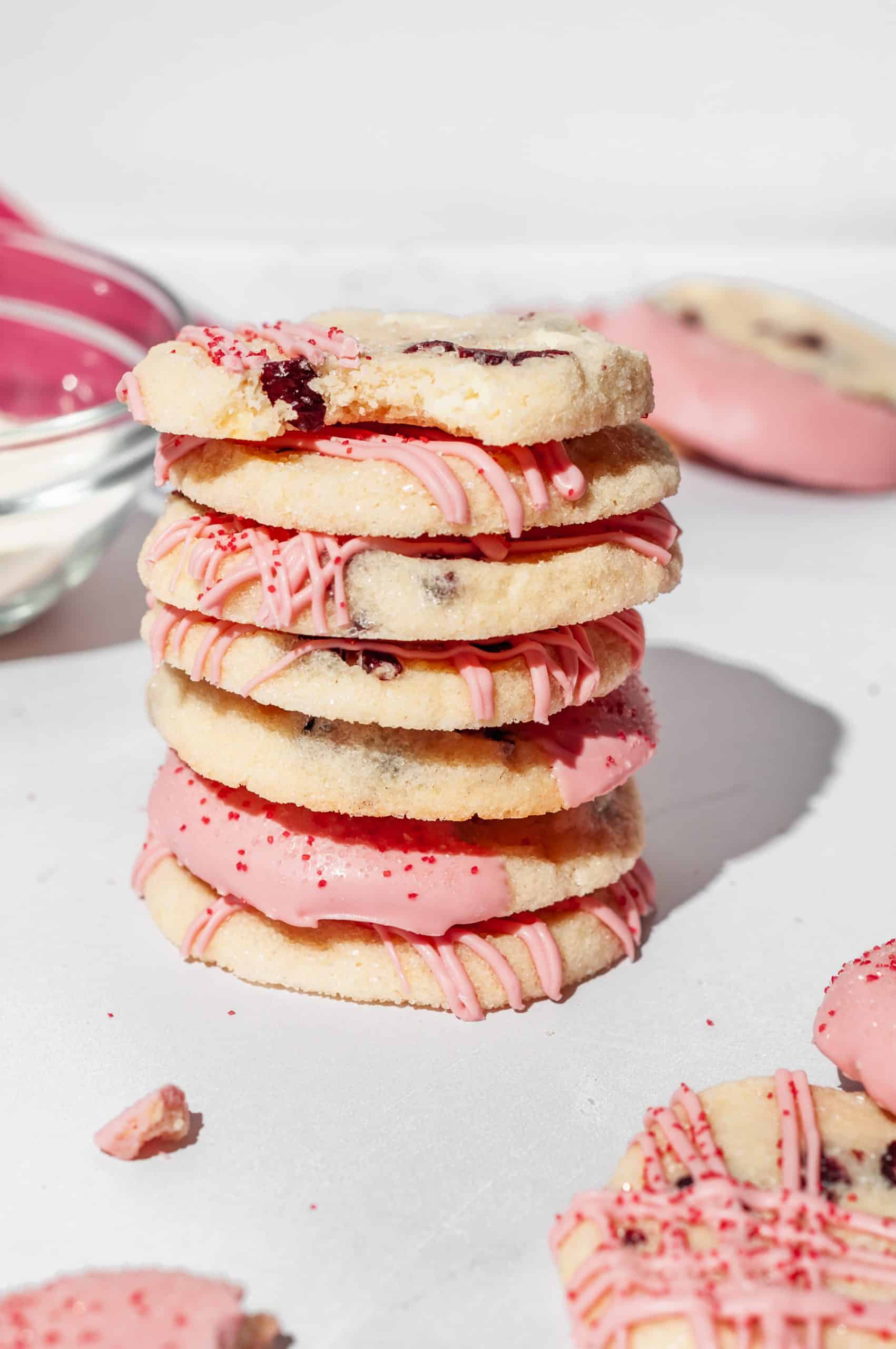 stack of cranberry shortbread cookies drizzled with pink white chocolate and red sugar
