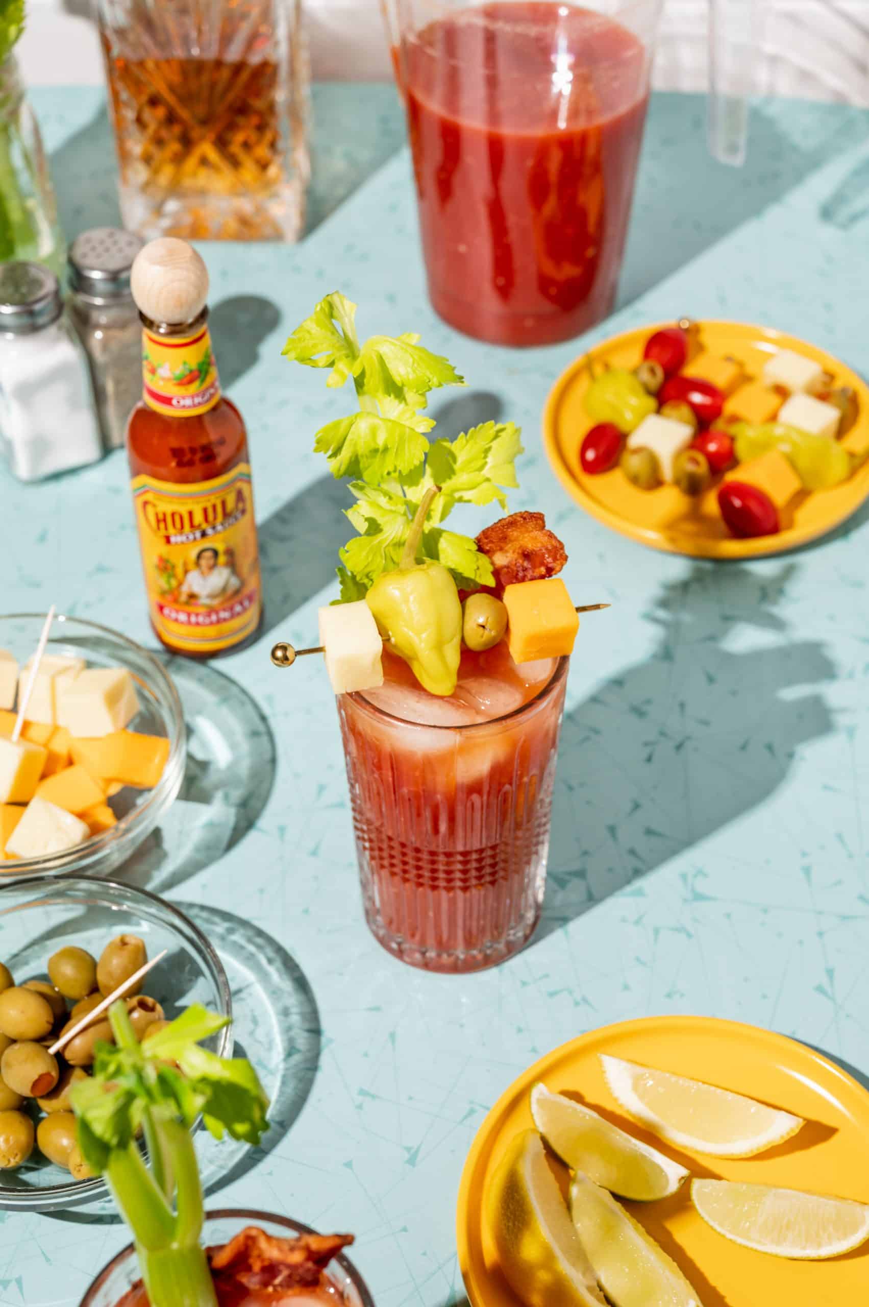 A bloody mary with a strip of bacon, celery, and a cocktail pick with more garnishes