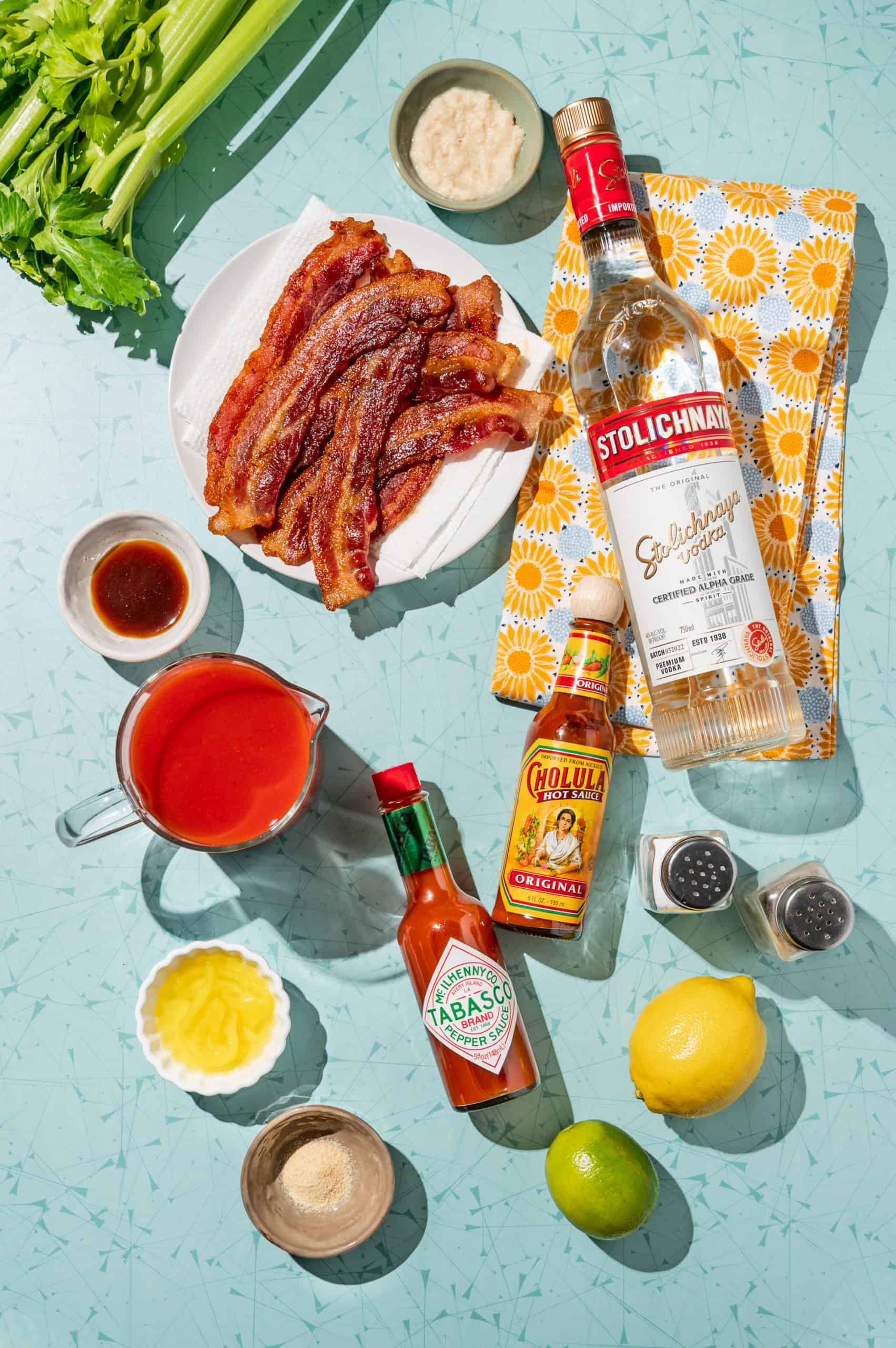 ingredients to make a bloody mary: vodka, tomato juice, bacon, hot sauce, lemon, horseradish, Worcestershire, celery