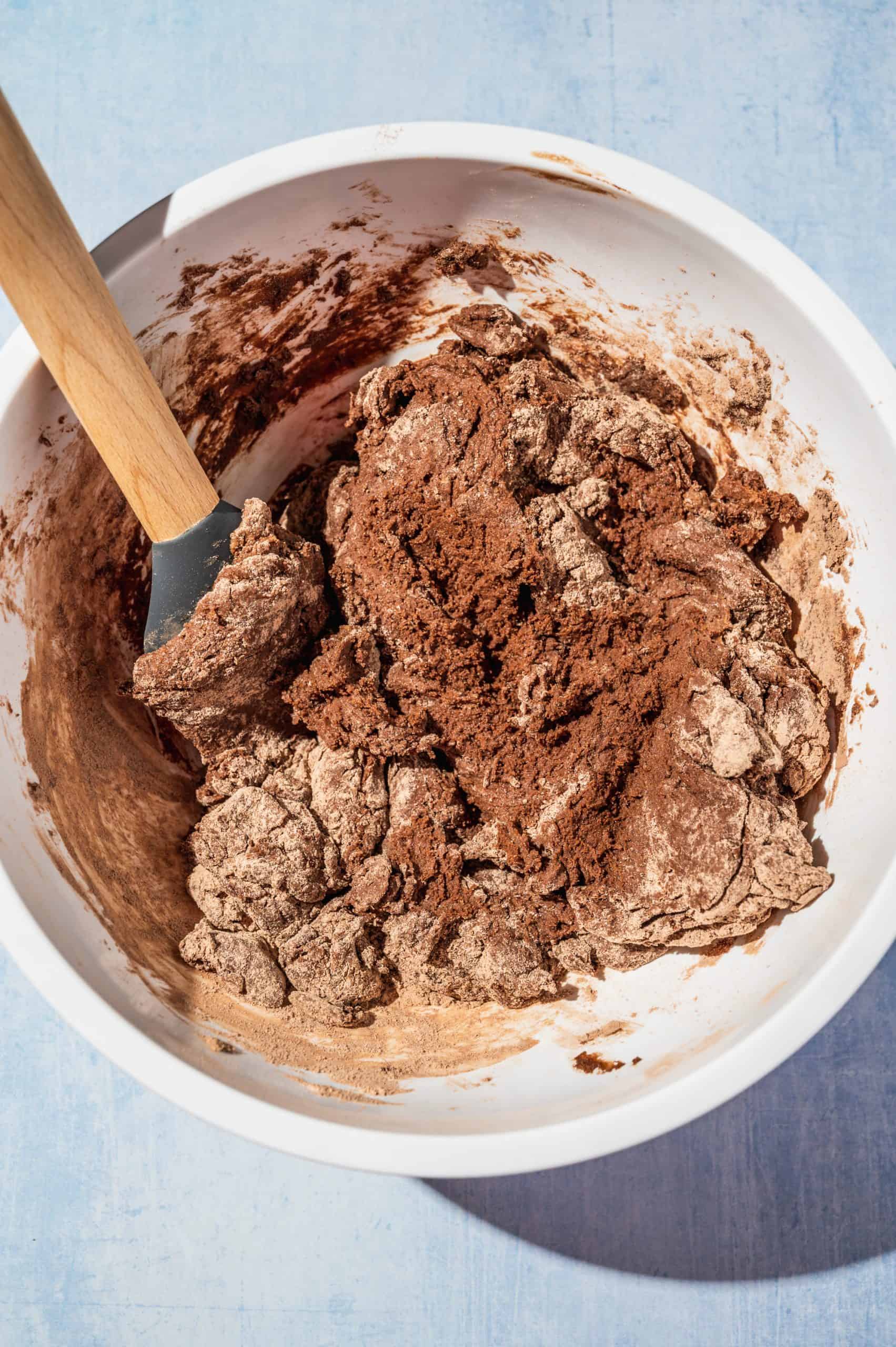 stiff shaggy chocolate donut dough in a white mixing bowl