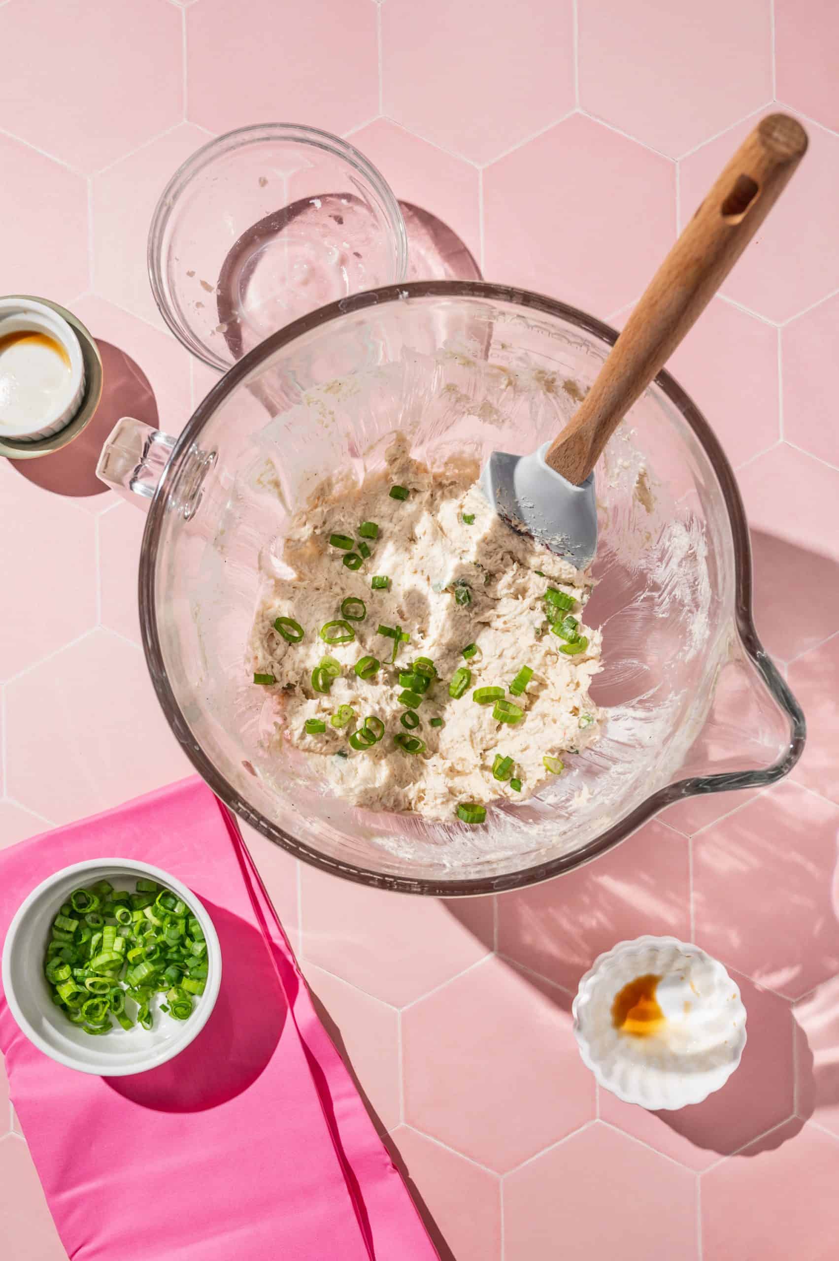 crab rangoon filling in a glass mixing bowl with chopped scallions on top