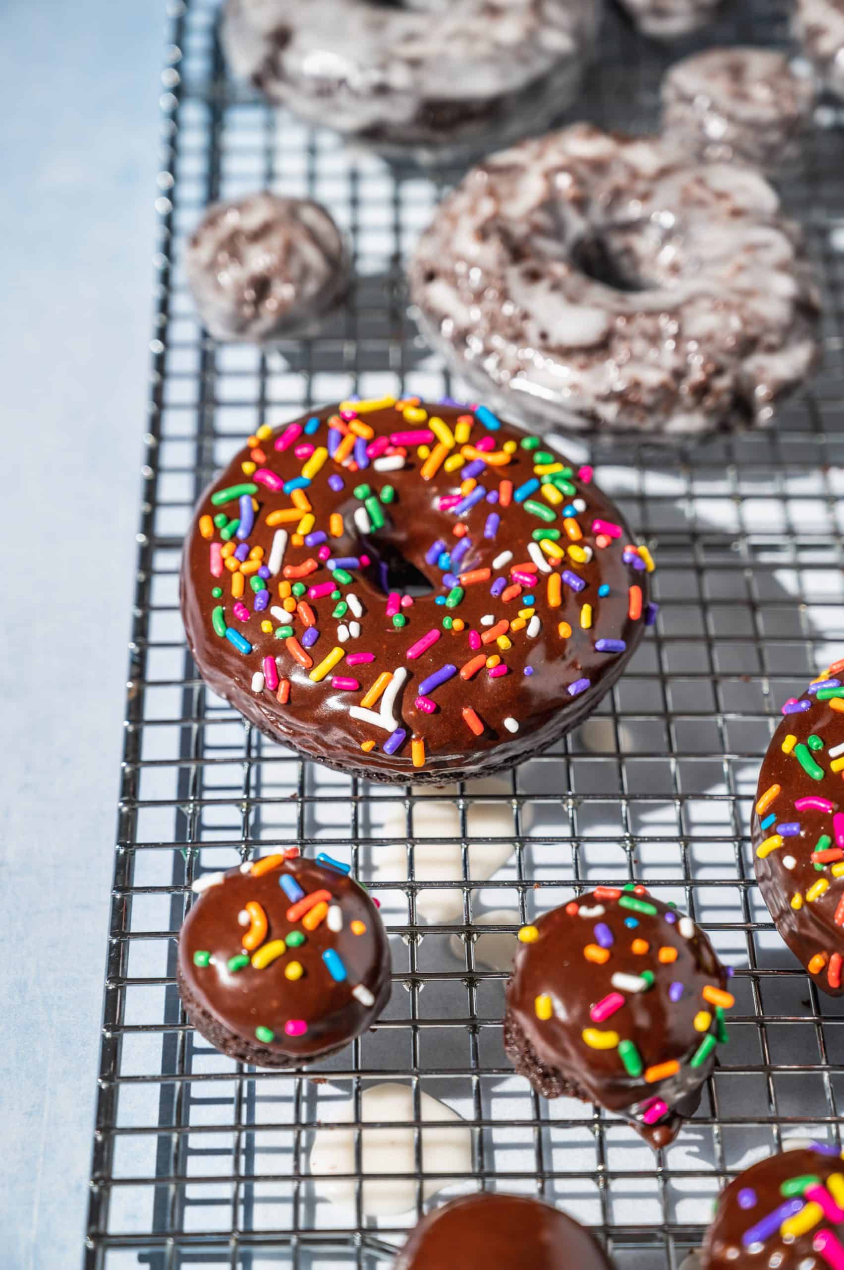 chocolate donuts drying on a wire rack after glazing