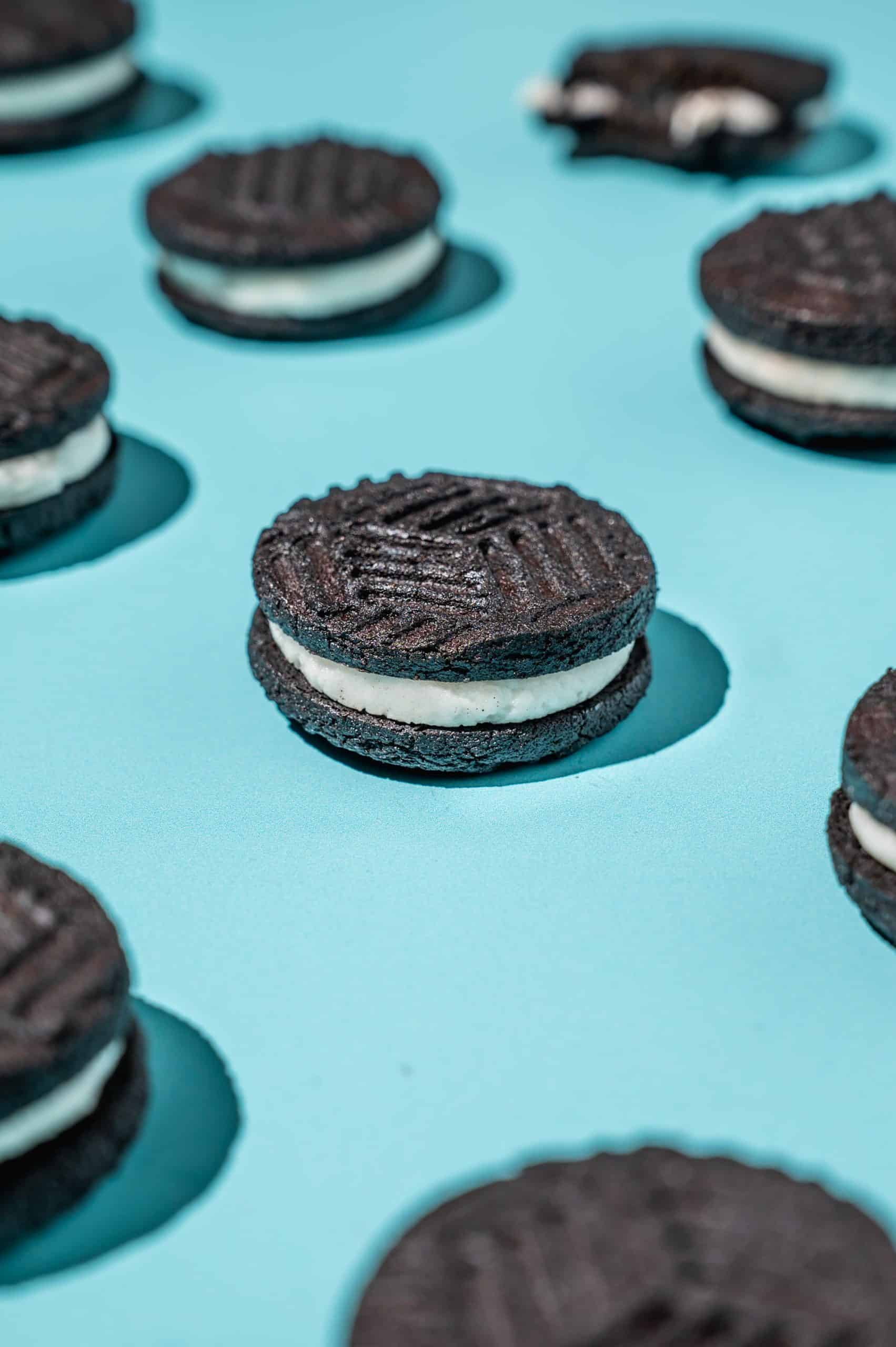 close up of homemade oreo cookies spaced in diagonal lines on a blue background