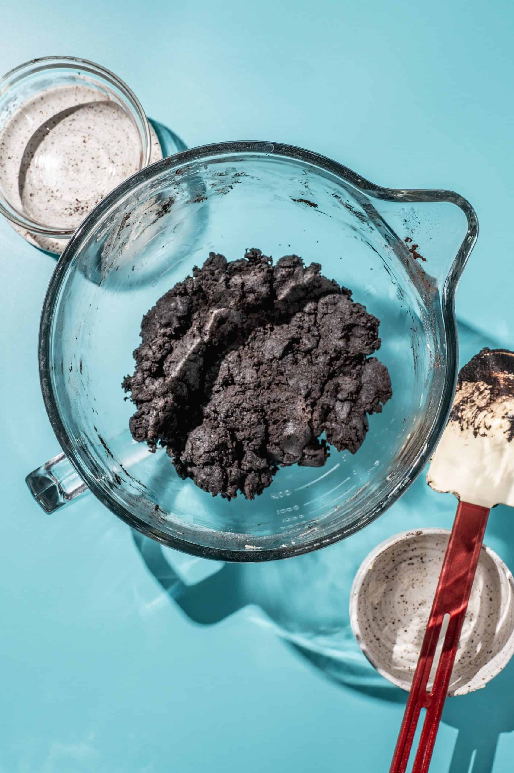 dark oreo cookie dough in a glass mixing bowl on a blue background
