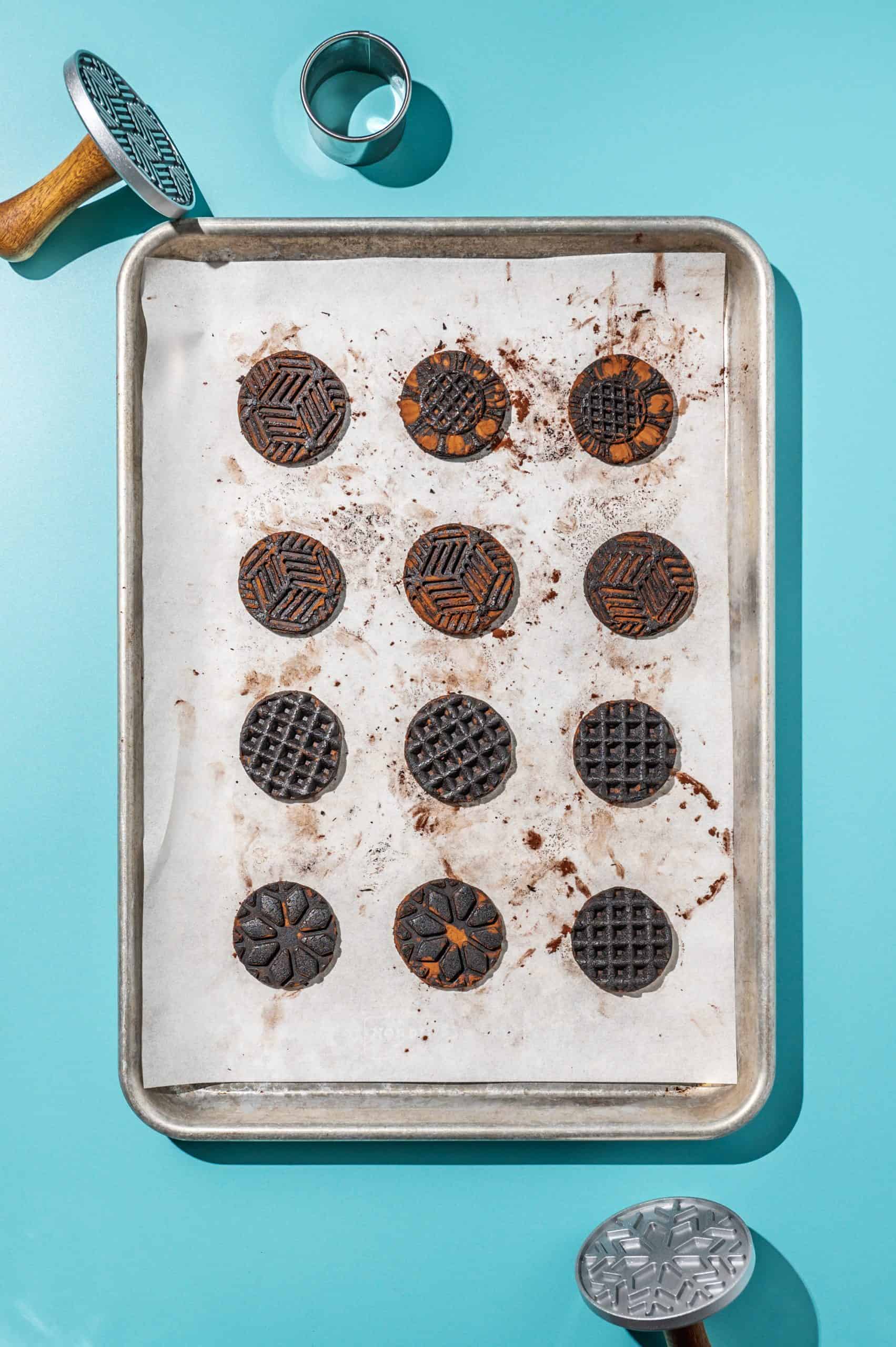 stamped chocolate wafer cookies for homemade oreos spaced on a baking sheet