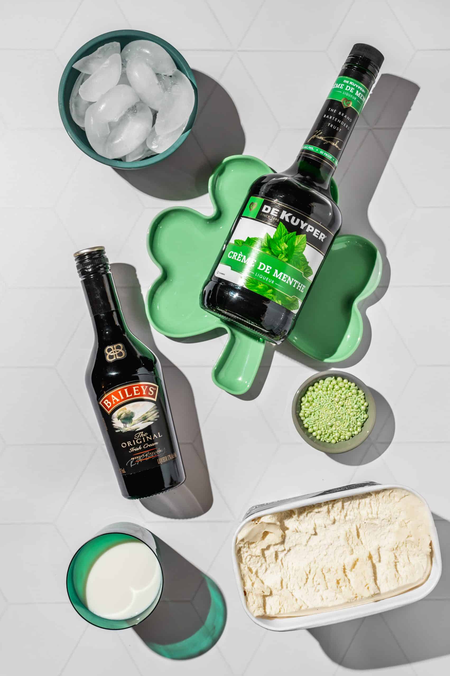 ingredients to make boozy shamrock shakes: creme de menthe, Irish cream, ice, ice cream, and milk