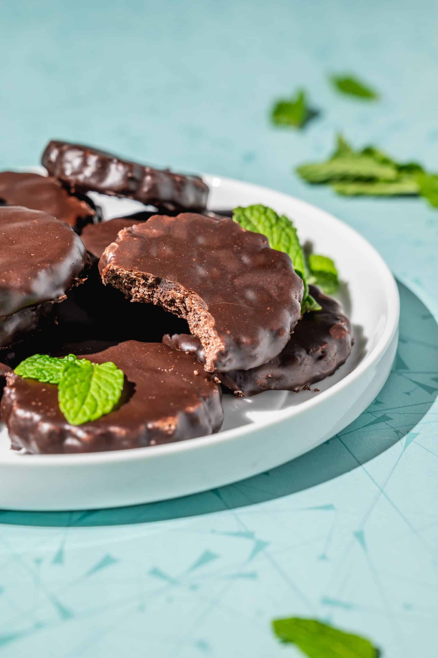 copycat thin mints on a white platter, one with a bite out to show crisp interior