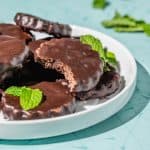 copycat thin mints on a white platter, one with a bite out to show crisp interior