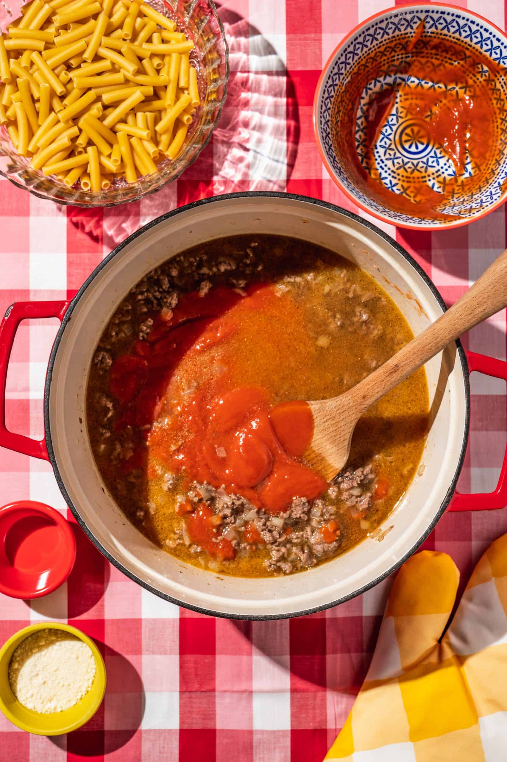 large pot filled liquidy ground beef and tomato soup mixture, stirring with wooden spoon