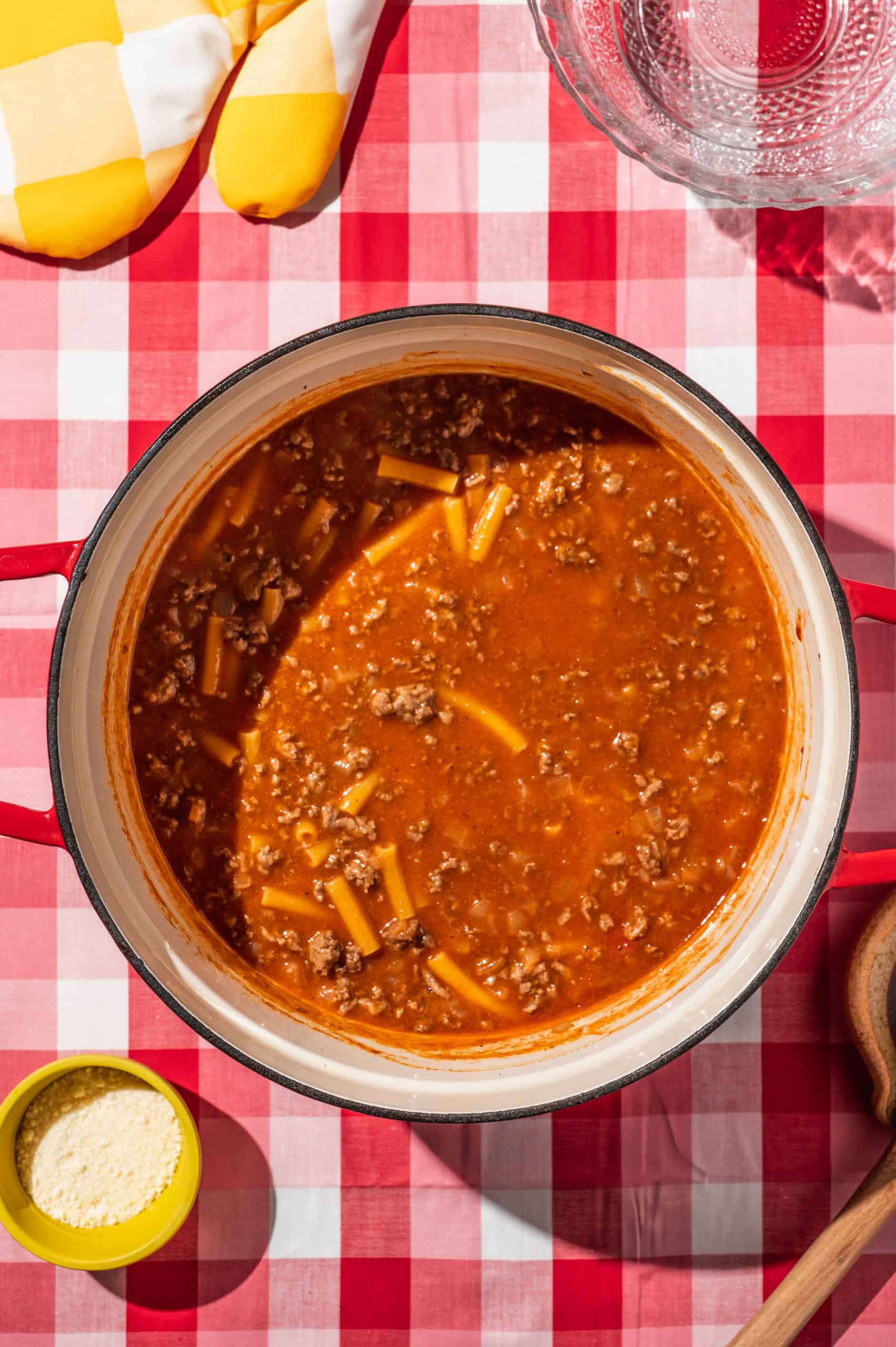 large red Dutch oven with tomato, beef, and ziti mixture