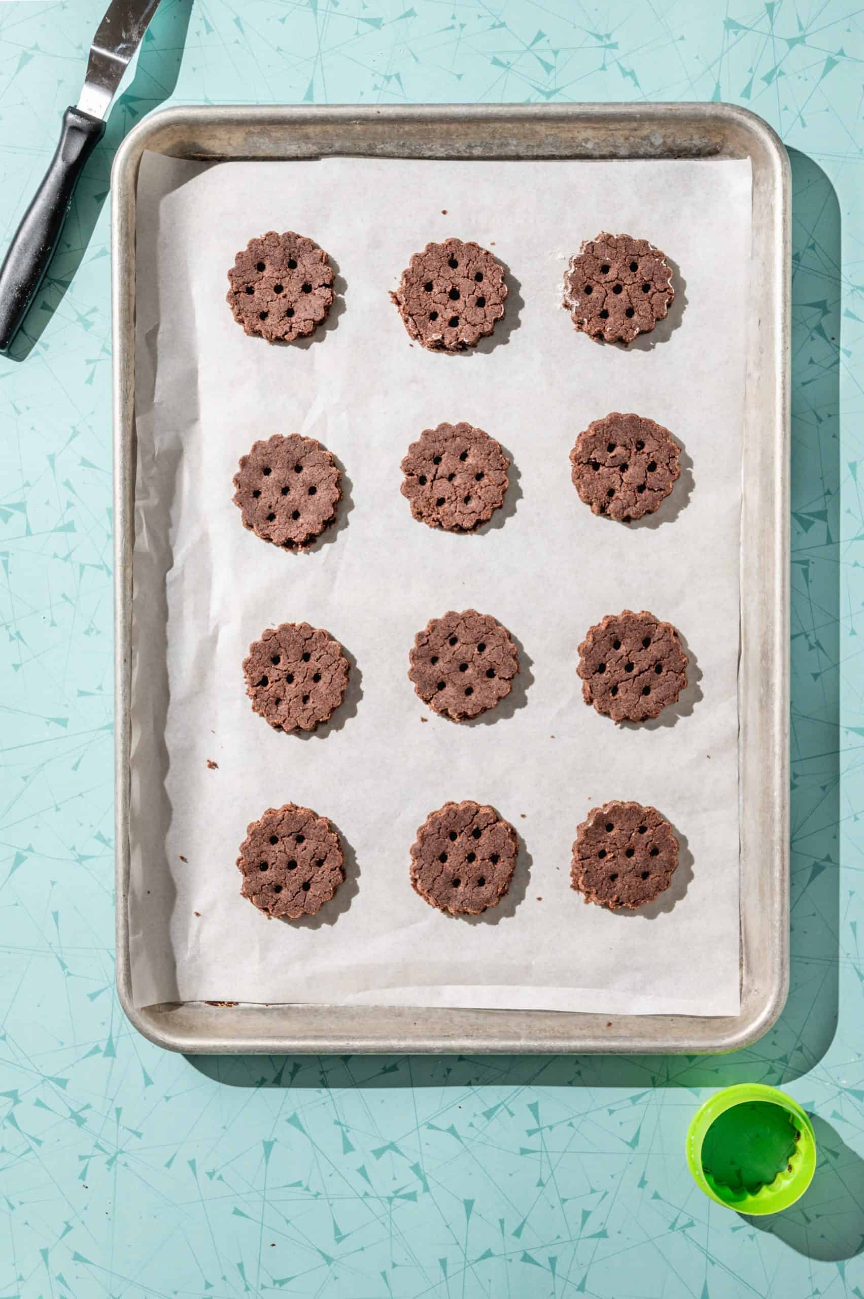 chocolate mint wafer cookies with scalloped edges spaced out on a cookie tray